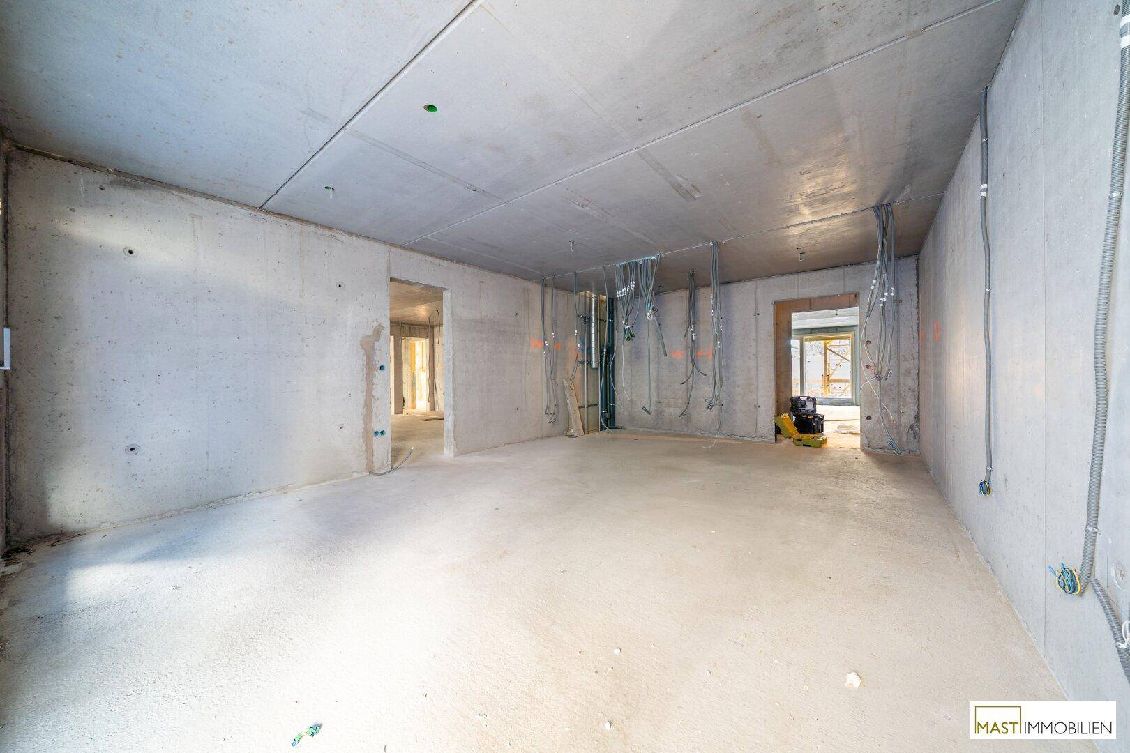 Geräumiger Rohbau-Innenraum mit Betonwänden und Decken, bereit für die weitere Gestaltung und Fertigstellung.