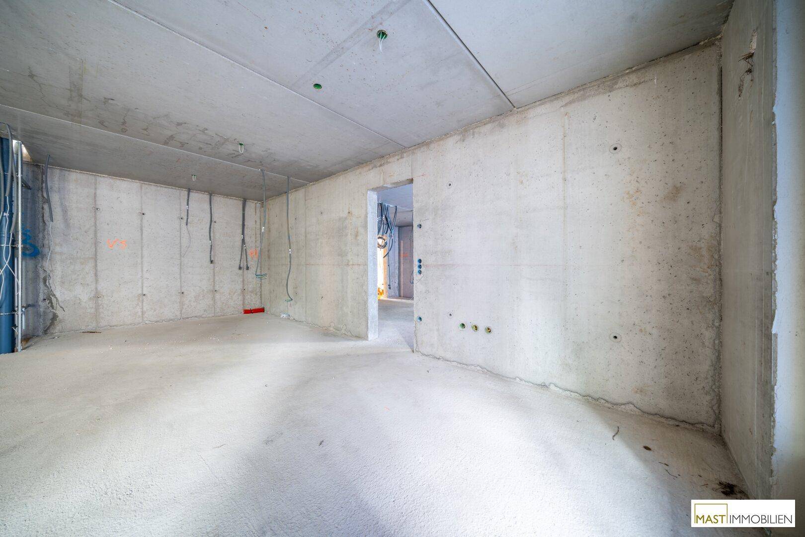 Leerer Rohbau-Raum mit Betonwänden und Decken, der viel Potenzial für individuelle Gestaltung bietet.
