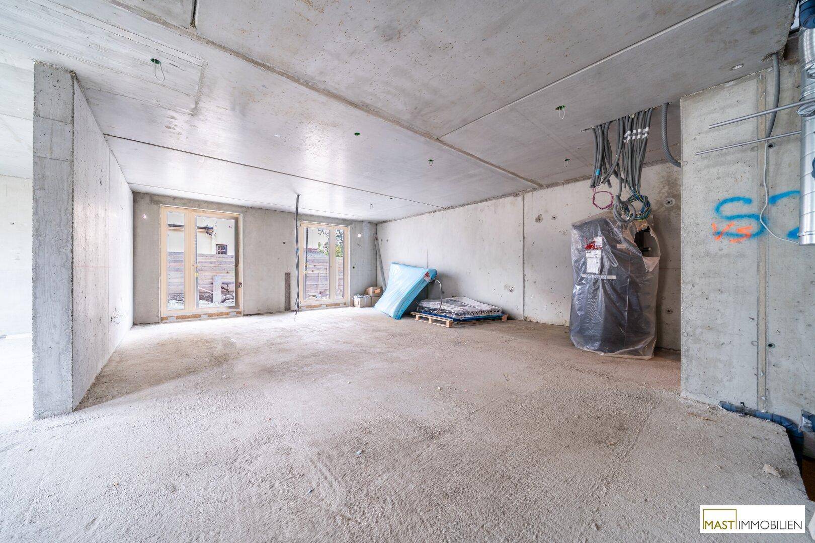 Rohbau-Innenraum mit Betonoberflächen und sichtbaren Installationen im Bauzustand.