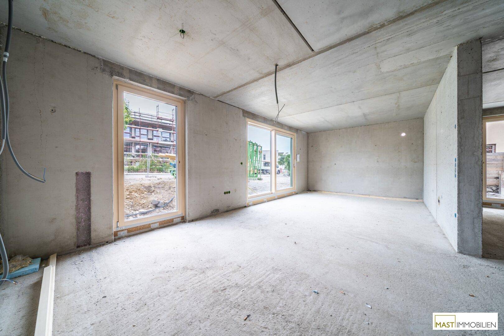 Heller Rohbau mit großen Fensterfronten und Betonwänden, ideal für individuelle Gestaltung.