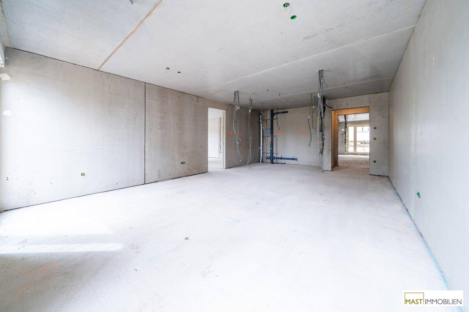 Unausgebauter Innenbereich mit Betonwänden und Decken, vorbereitet für weitere Installationen.