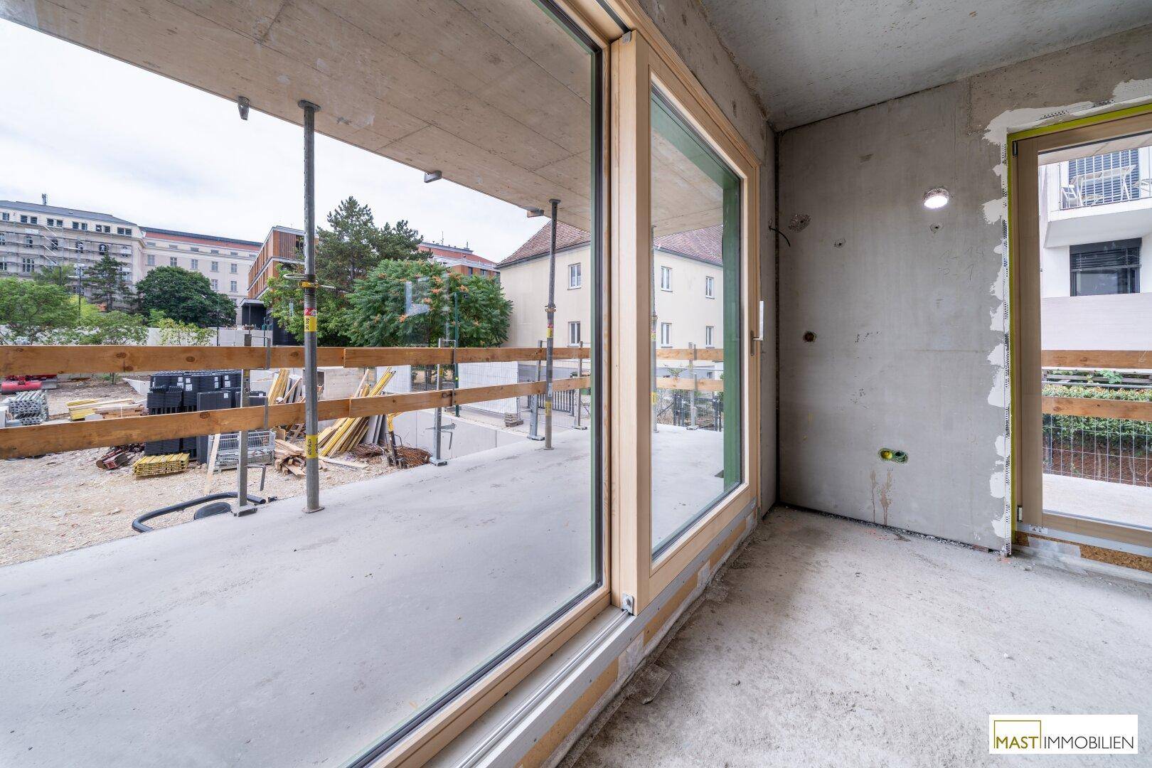 Unfertige Terrasse mit großen Fenstern, die den Blick auf die Baustelle freigeben.