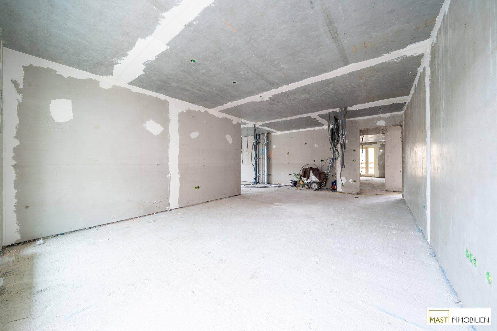 Unfertiger Innenraum mit Rohbauwänden und sichtbaren Installationen, bereit für den Ausbau.