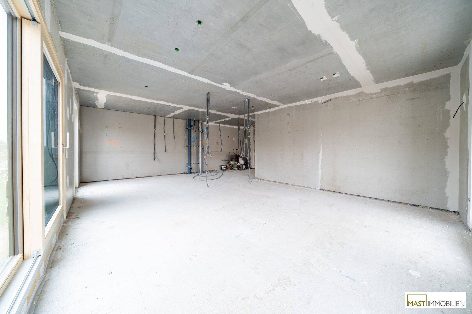 Unfertiger Innenraum mit Rohbauwänden und sichtbaren Installationen, bereit für den weiteren Ausbau.