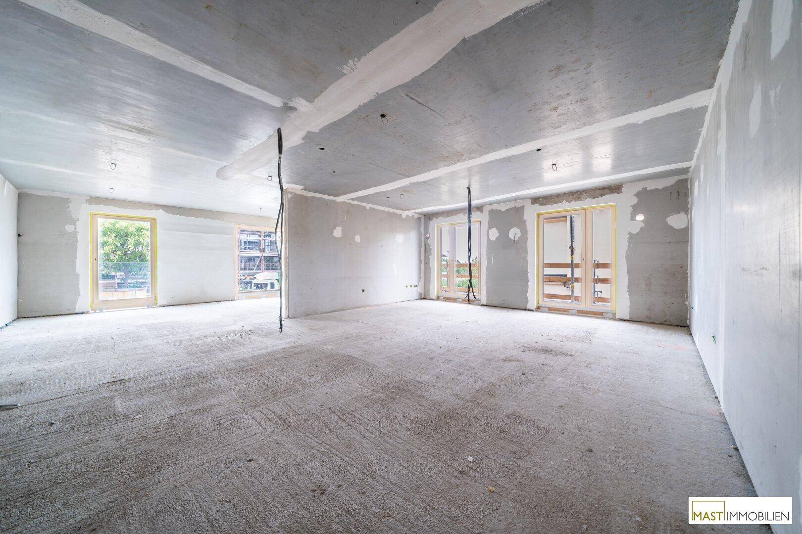Großer, unfertiger Raum mit Betonwänden und -decken, bereit für den Innenausbau.