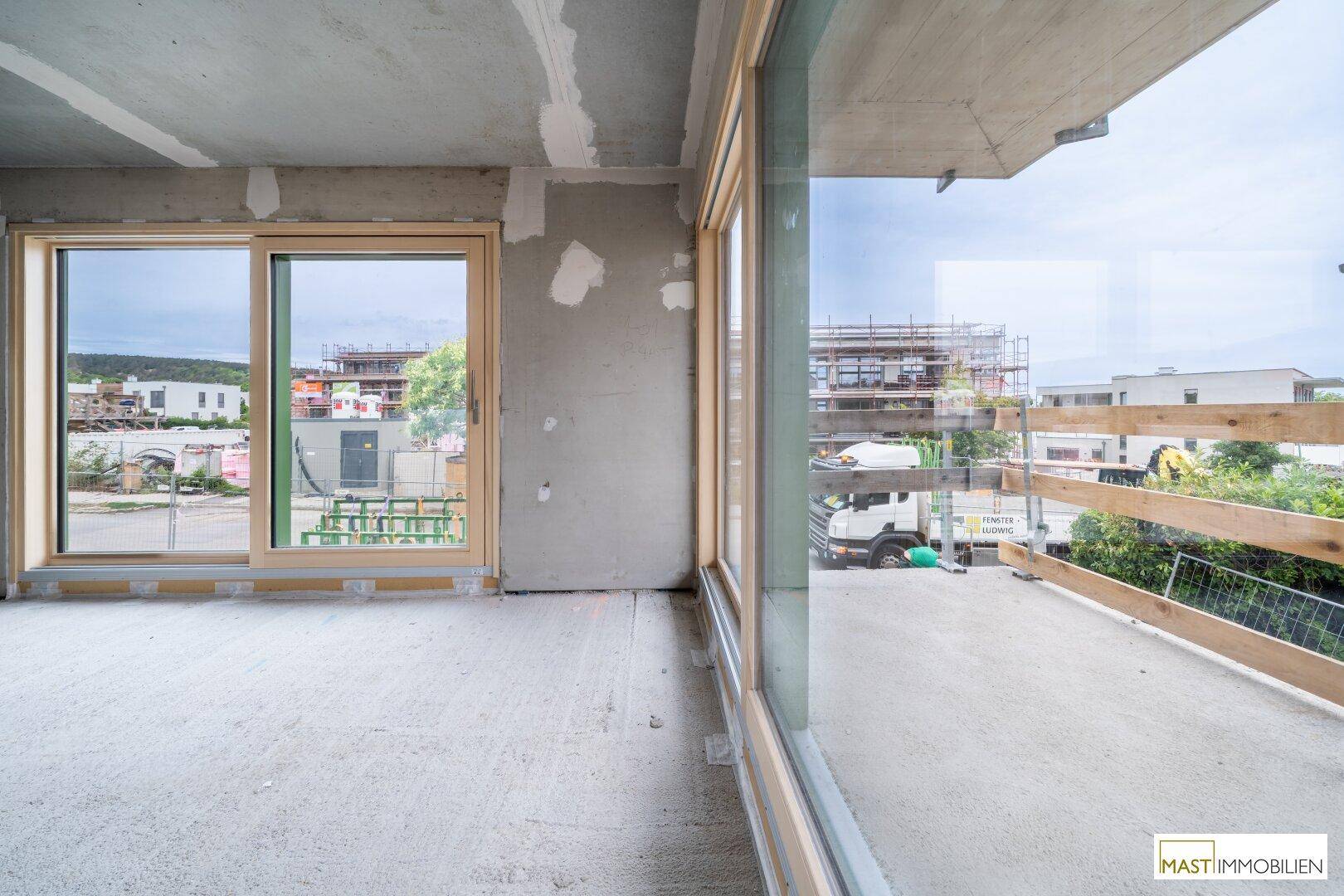 Große Fensterfronten im Rohbau mit Blick auf die Baustelle und die Umgebung.