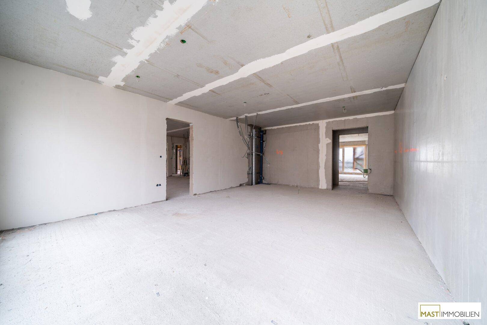 Rohbau-Innenraum mit Betonwänden und Decken, vorbereitet für den weiteren Innenausbau und Installationen.