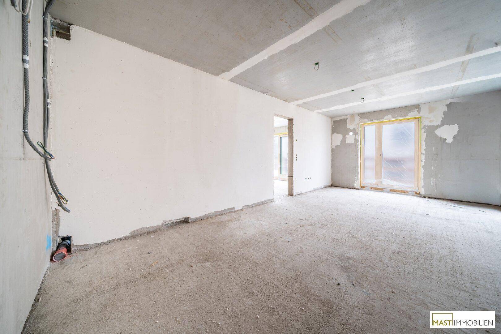 Unfertiger Raum mit Betonboden und Fensteröffnung, zeigt den aktuellen Bauzustand vor dem Ausbau.