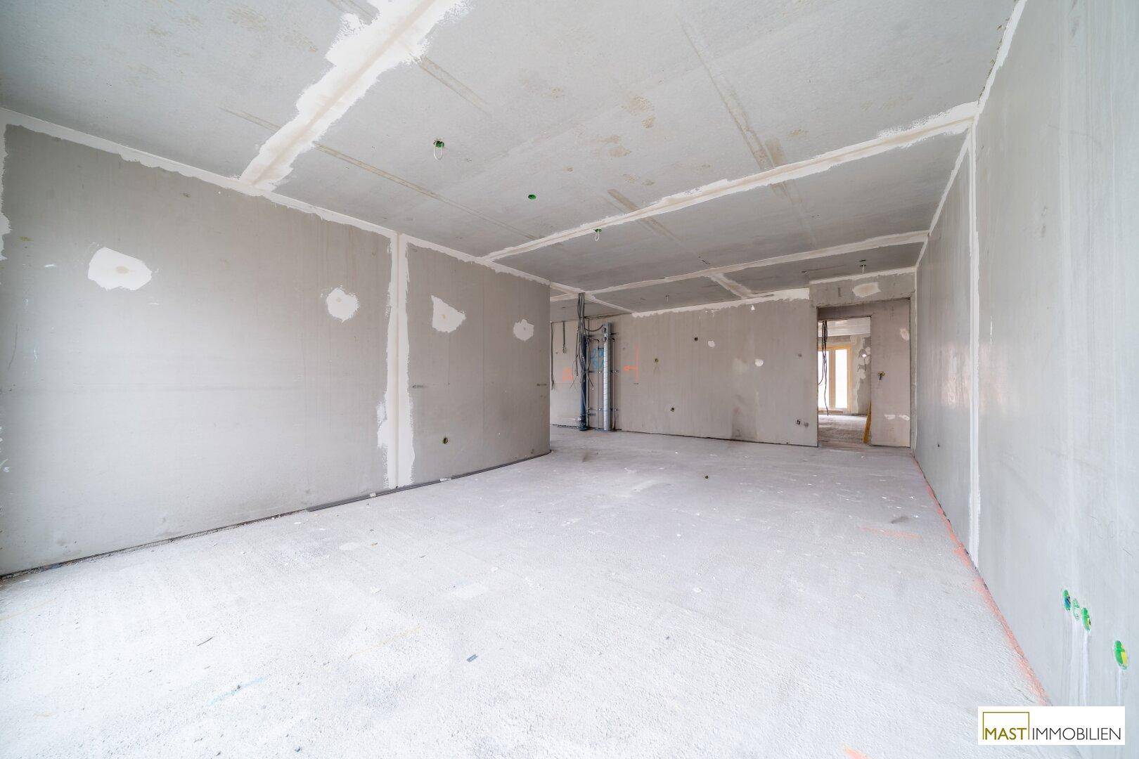 Rohbau eines Innenraums mit Betonboden und unverputzten Wänden, bereit für den Innenausbau.