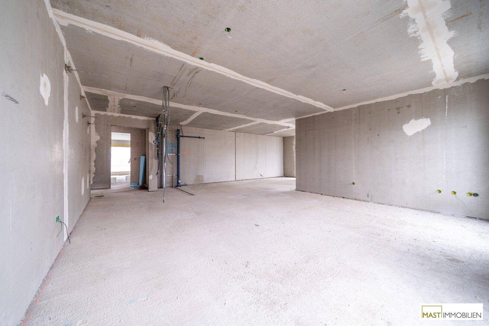 Unfertiger Innenraum mit Rohbauwänden und Betonboden, bereit für den weiteren Ausbau.