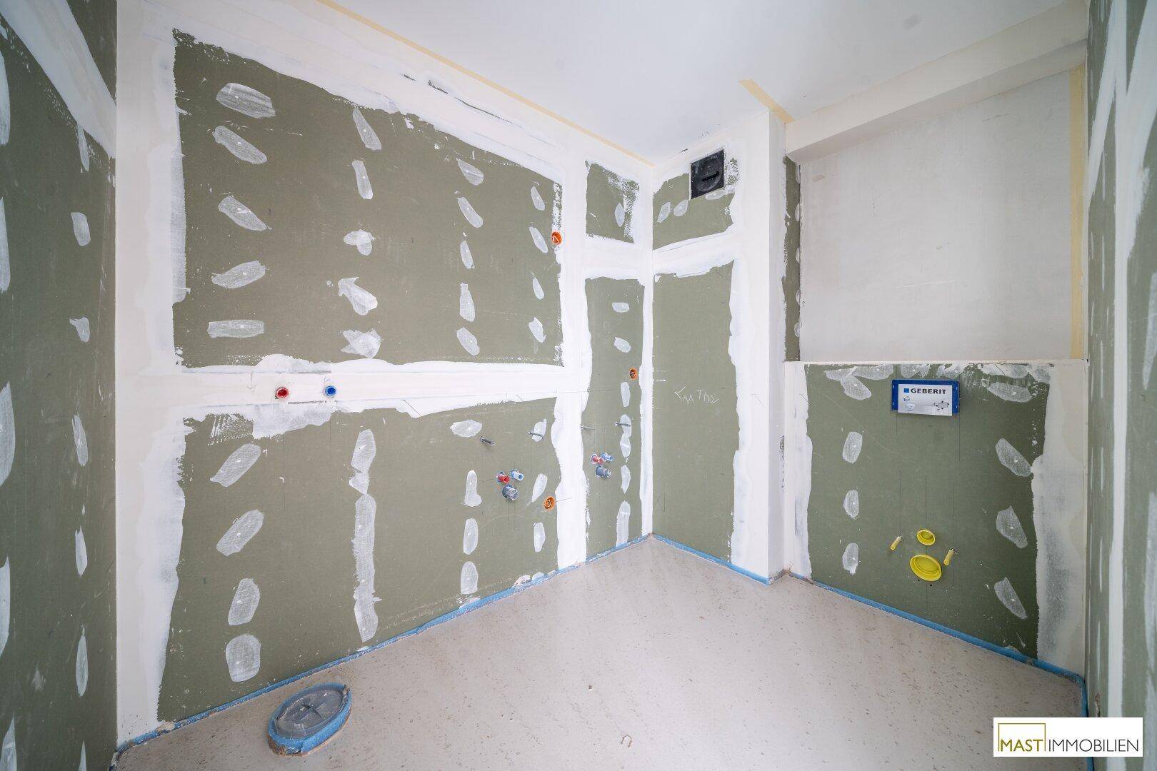 Rohbau-Badezimmer mit vorbereiteten Anschlüssen für Dusche, Waschbecken und Toilette im Neubau.