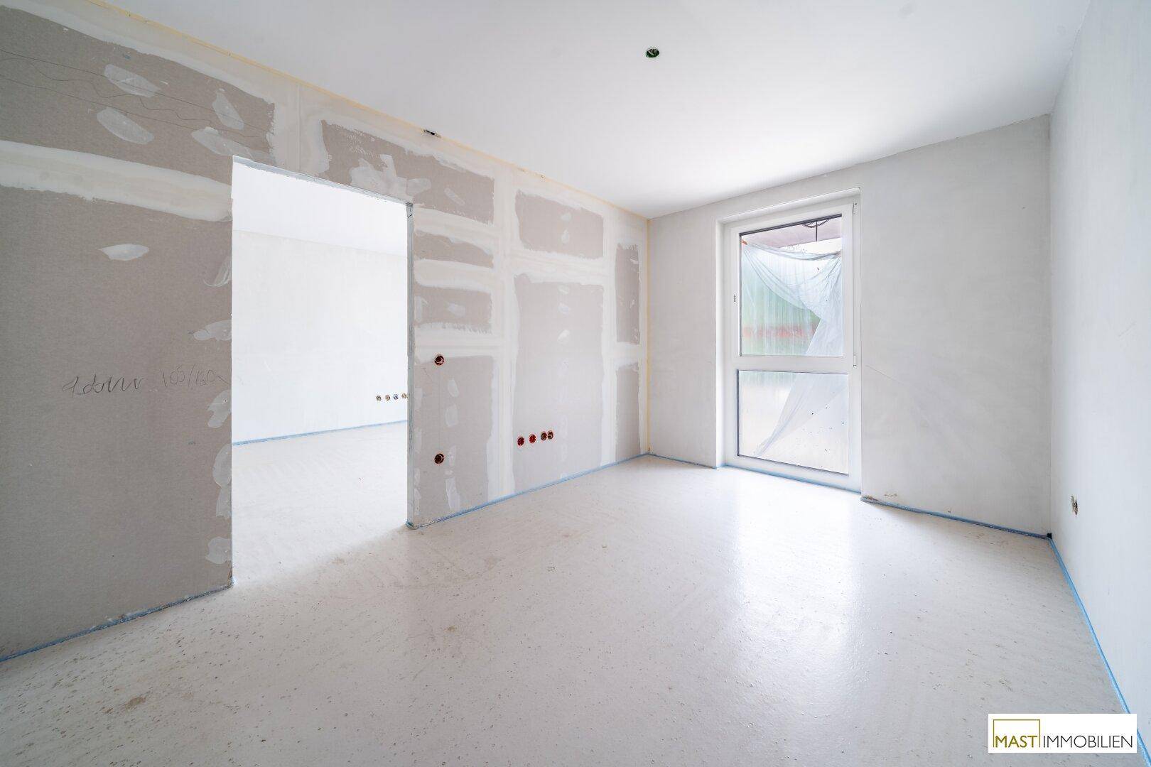 Heller Rohbau-Raum mit Fenster und vorbereiteten Wänden für den Innenausbau in einem Neubau.