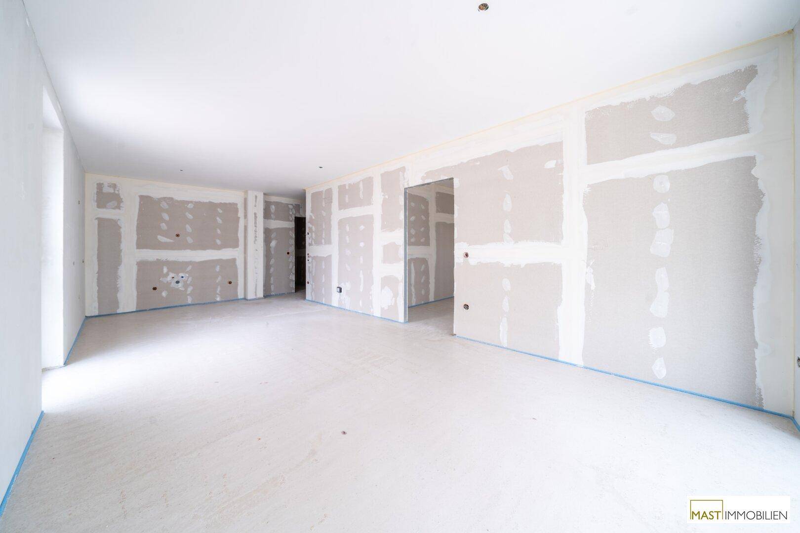 Geräumiger Innenraum im Rohbau mit vorbereiteten Wänden für den Ausbau und hellem Ambiente.