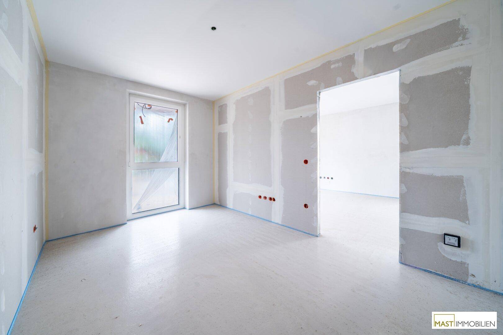 Heller Raum im Rohbau mit Fenster, bereit für den Innenausbau und zukünftige Nutzung.