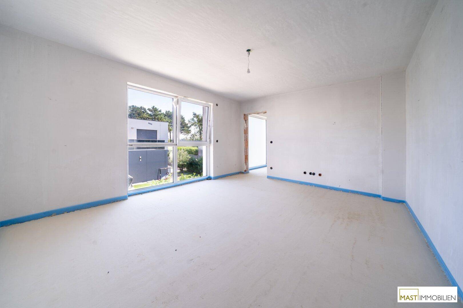 Helles, unfertiges Schlafzimmer mit großen Fenstern, die den Raum mit natürlichem Licht durchfluten.