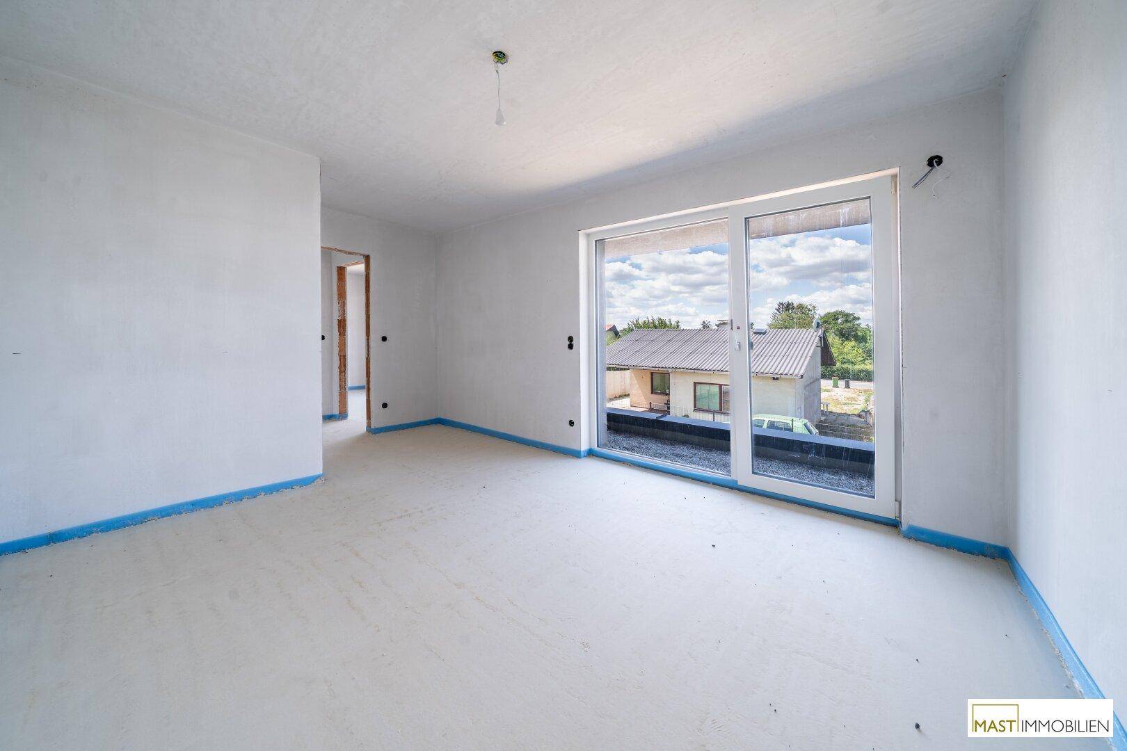 Unfertiges Schlafzimmer mit großen Glasfronten, die Zugang zu einem möglichen Balkon oder einer Terrasse bieten.