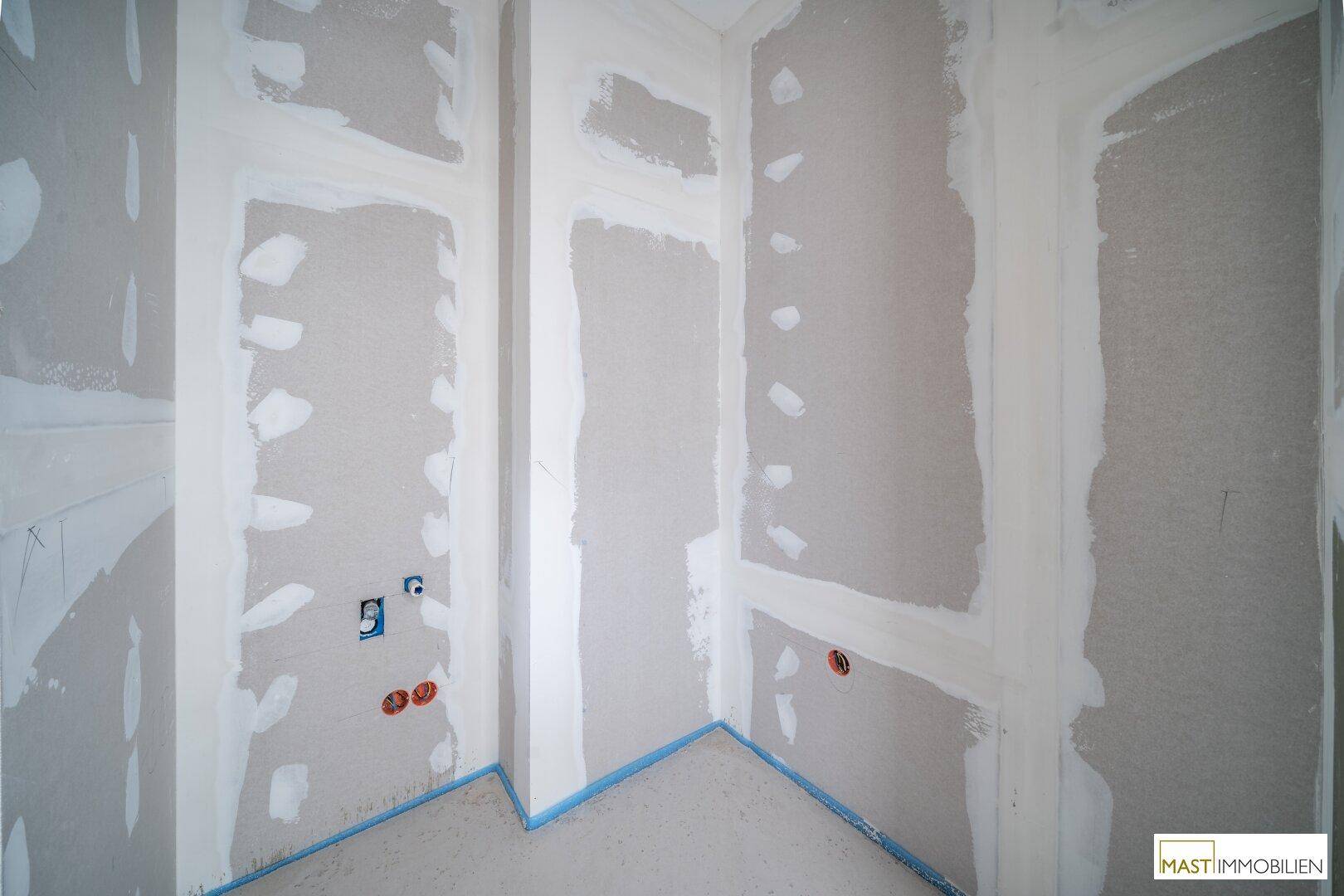 Kleiner Raum im Rohbau mit vorbereiteten Anschlüssen für ein Gäste-WC oder einen Abstellraum.