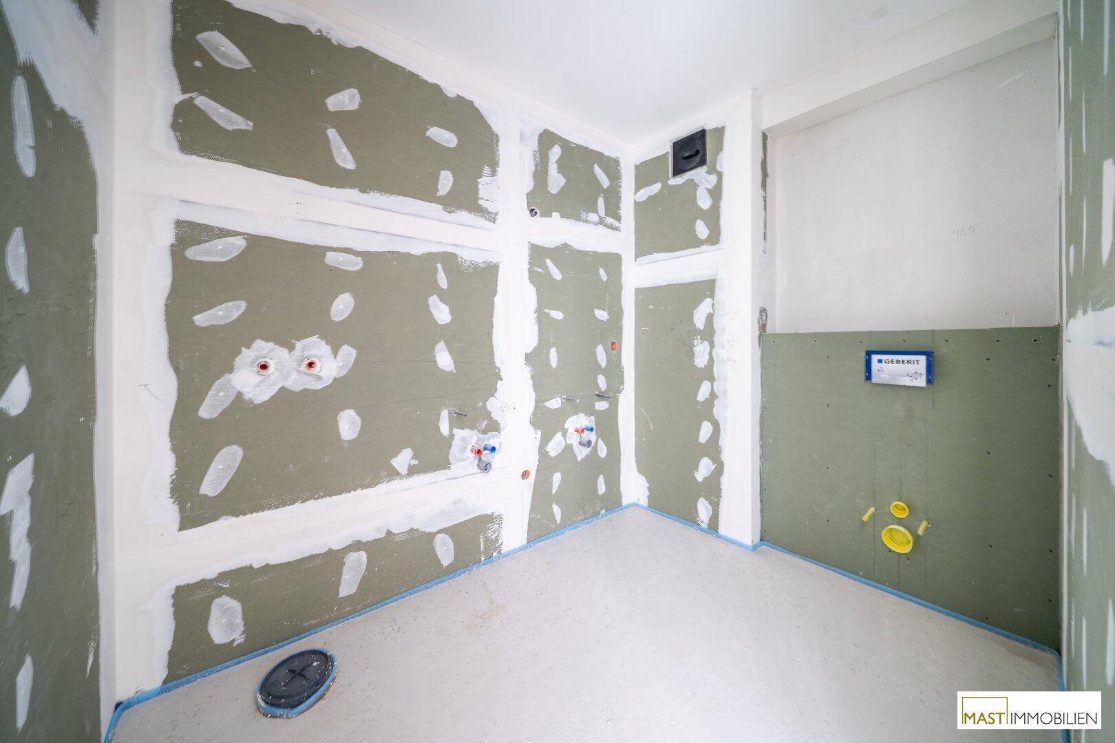 Badezimmer im Rohbau mit vorbereiteten Wasseranschlüssen und feuchtigkeitsbeständigen Wänden für die Installation.