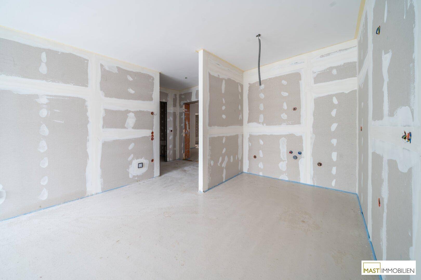 Innenraum im Rohbauzustand mit Trockenbauwänden und sichtbaren Elektroinstallationen für den Ausbau.