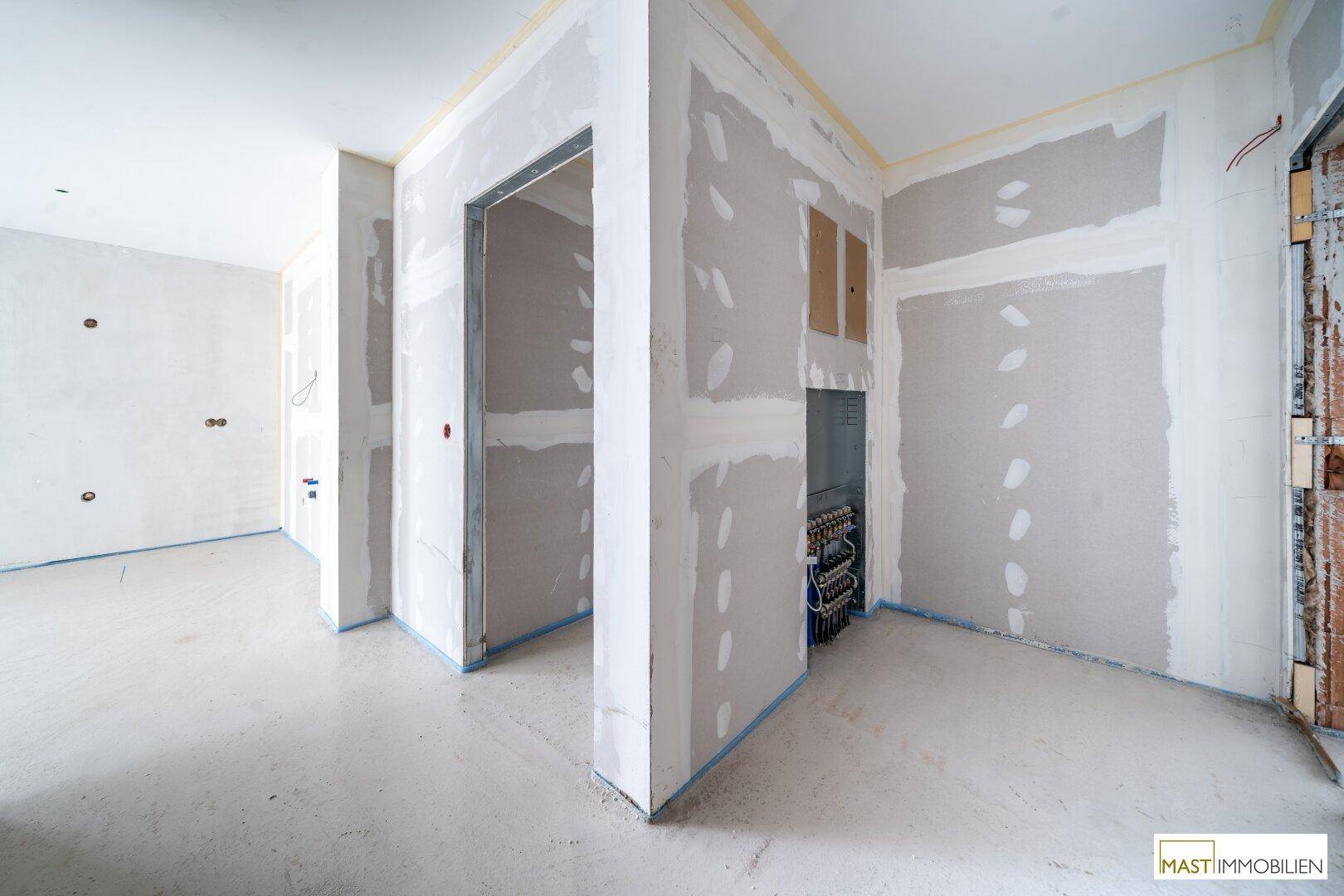 Rohbau-Innenraum mit Trockenbauwänden und sichtbaren Installationen, bereit für den Innenausbau.