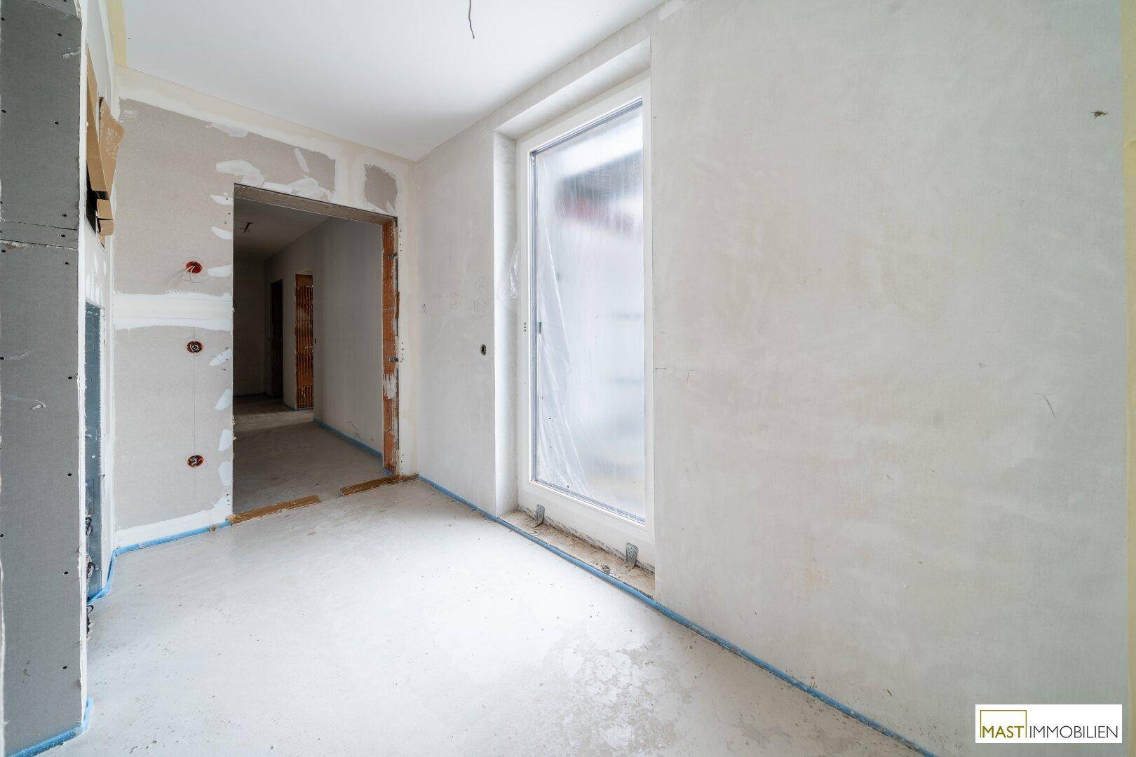 Rohbauzimmer mit Trockenbauwänden und einem mit Folie abgedeckten Fenster oder Tür.