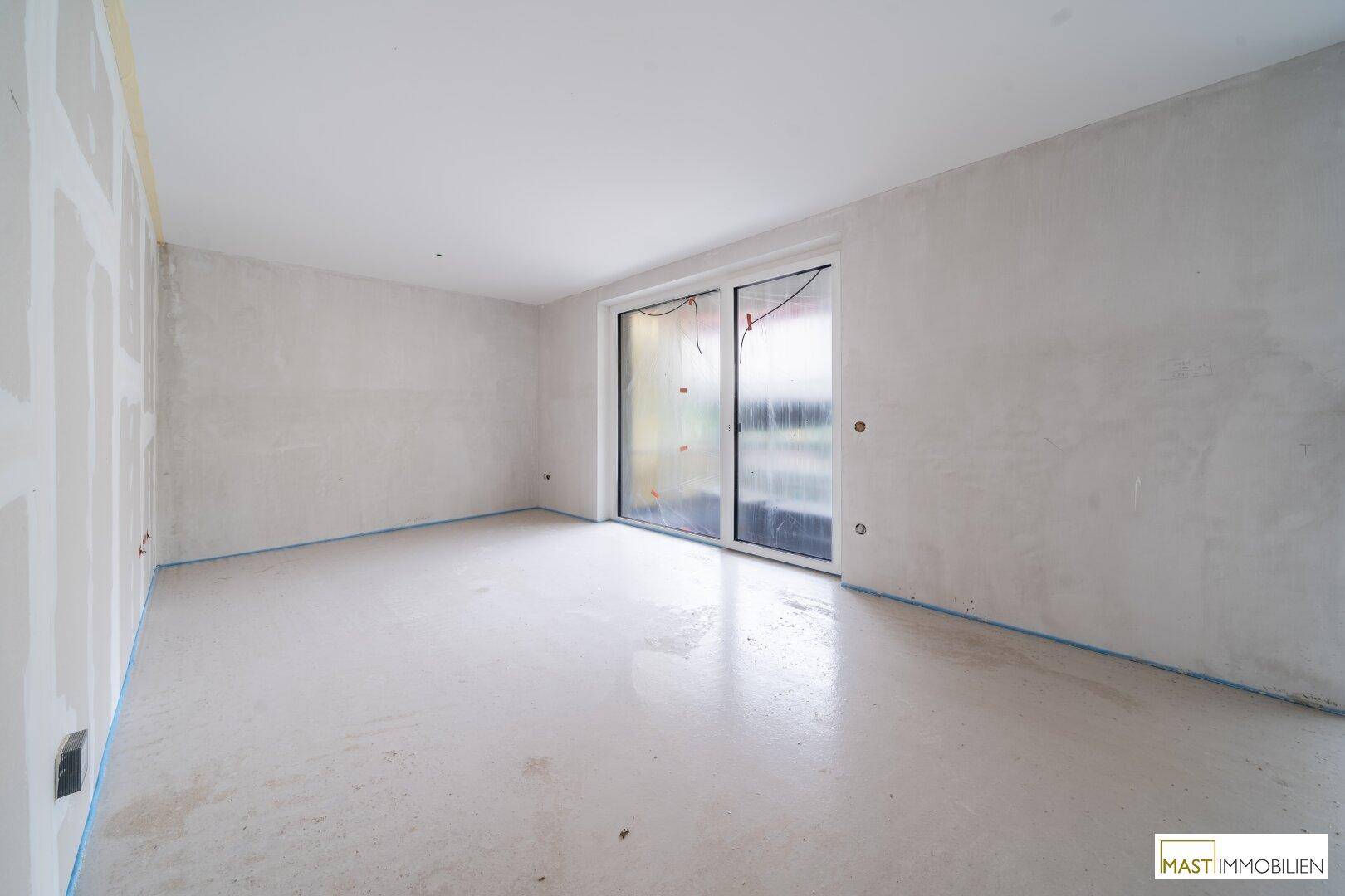 Geräumiger Rohbau mit großen, abgedeckten Fenstern, bereit für den weiteren Ausbau.