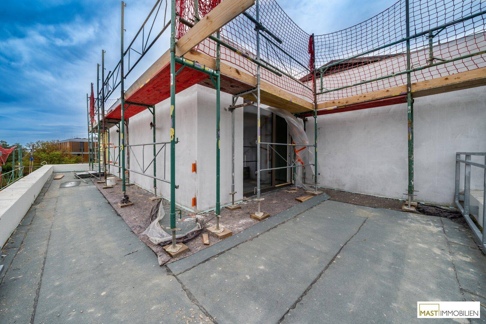 Dachterrasse im Bau mit Gerüst und Blick auf die Umgebung.