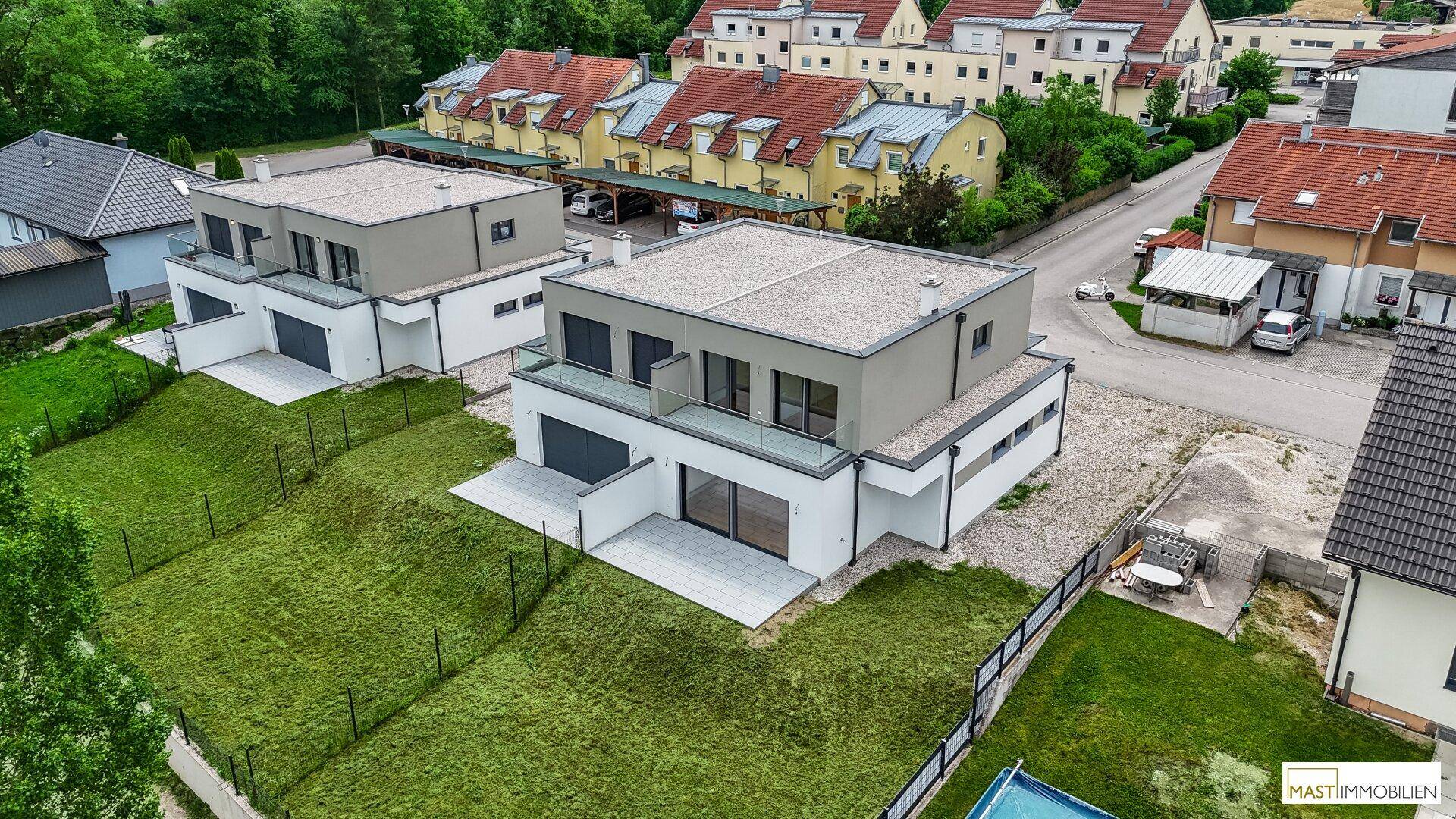 Luftaufnahme von zwei modernen Neubauhäusern mit Flachdach, großen Fenstern und angrenzendem Gartenbereich.