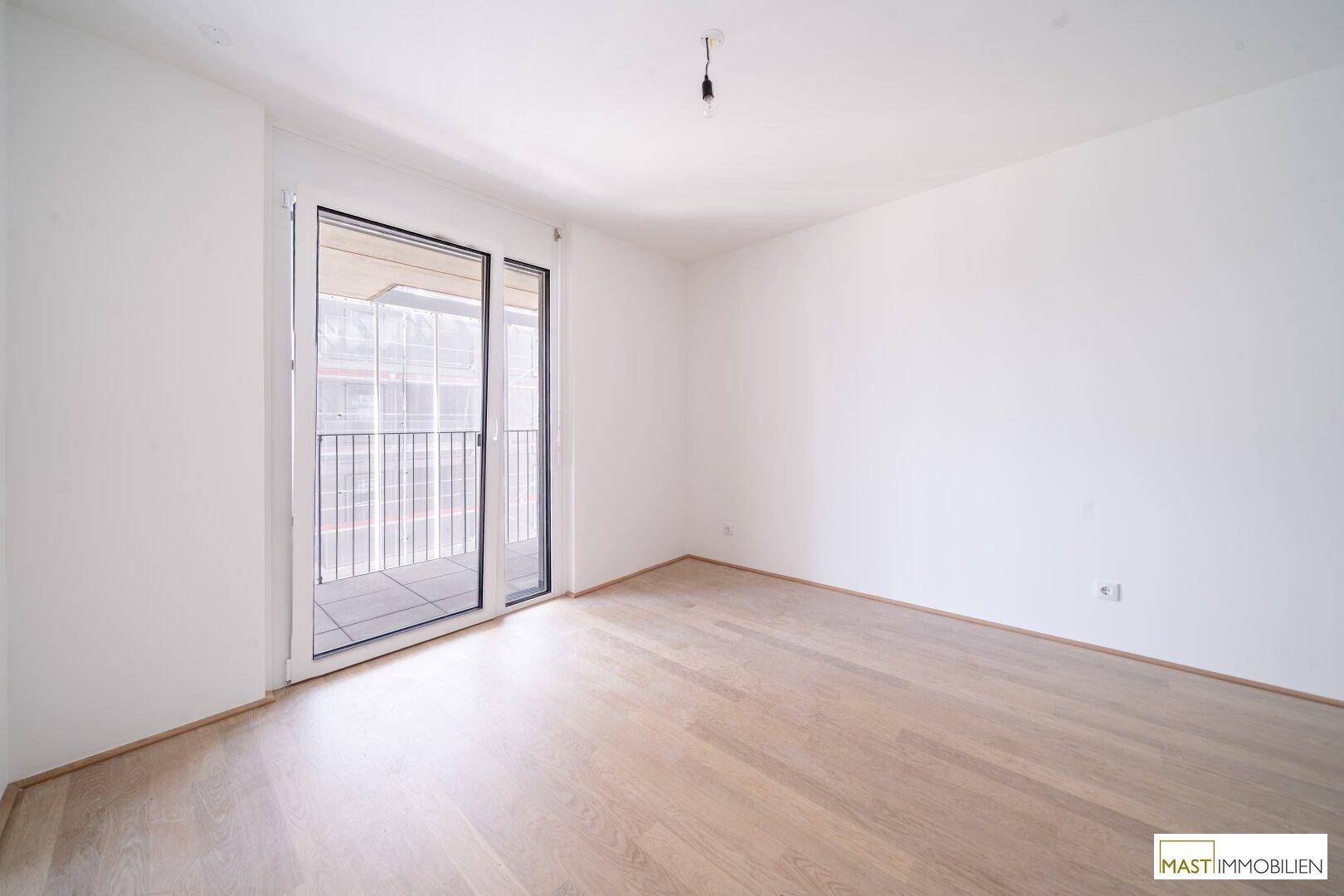 Helles, unmöbliertes Zimmer mit Balkonzugang und Holzboden, ideal für Schlaf- oder Arbeitsbereich.