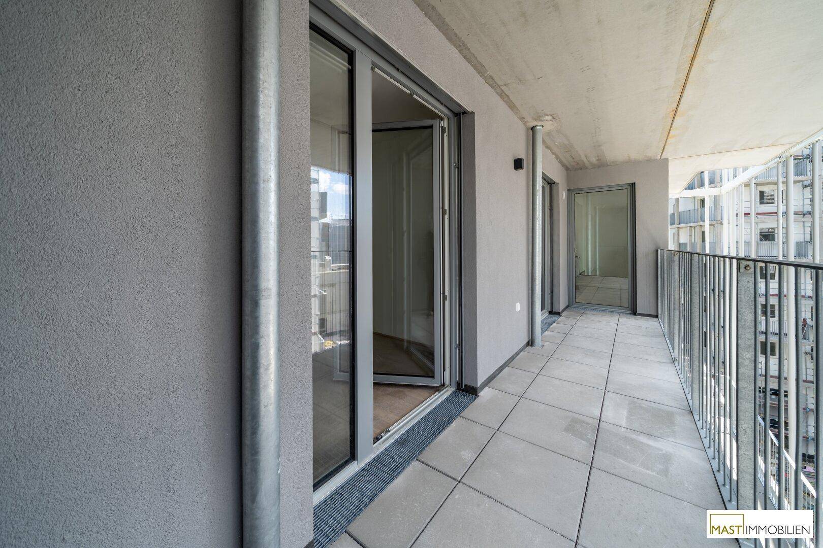 Langer Balkon mit Fliesenboden und Metallgeländer, bietet Platz für Outdoor-Möbel.