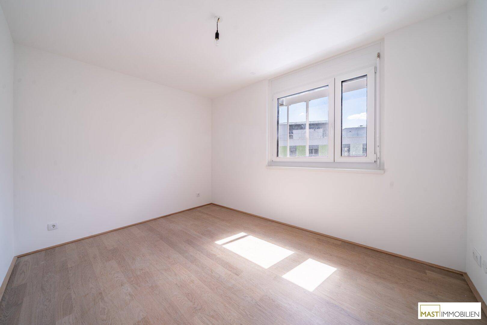 Helles Schlafzimmer mit großen Fenstern und neuem Holzparkettboden, bereit zum Einzug.