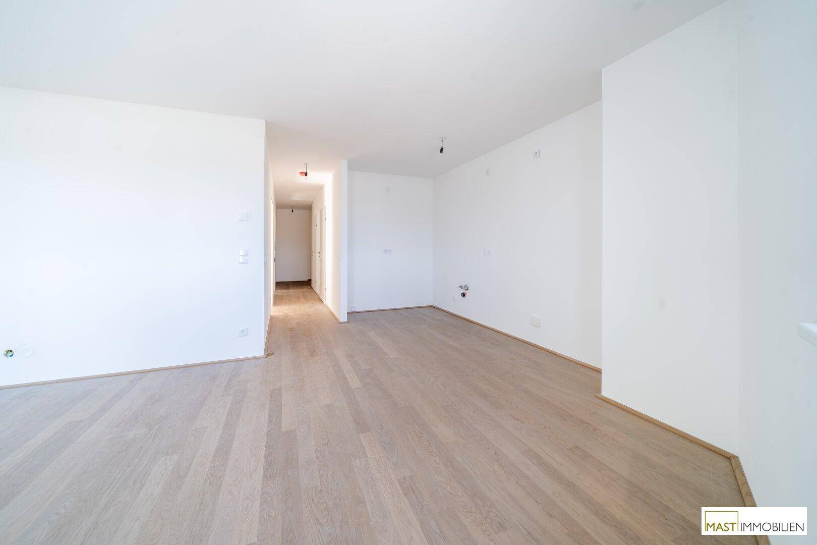 Heller Wohnbereich mit Laminatboden, der einen offenen Übergang zum Flur bietet.