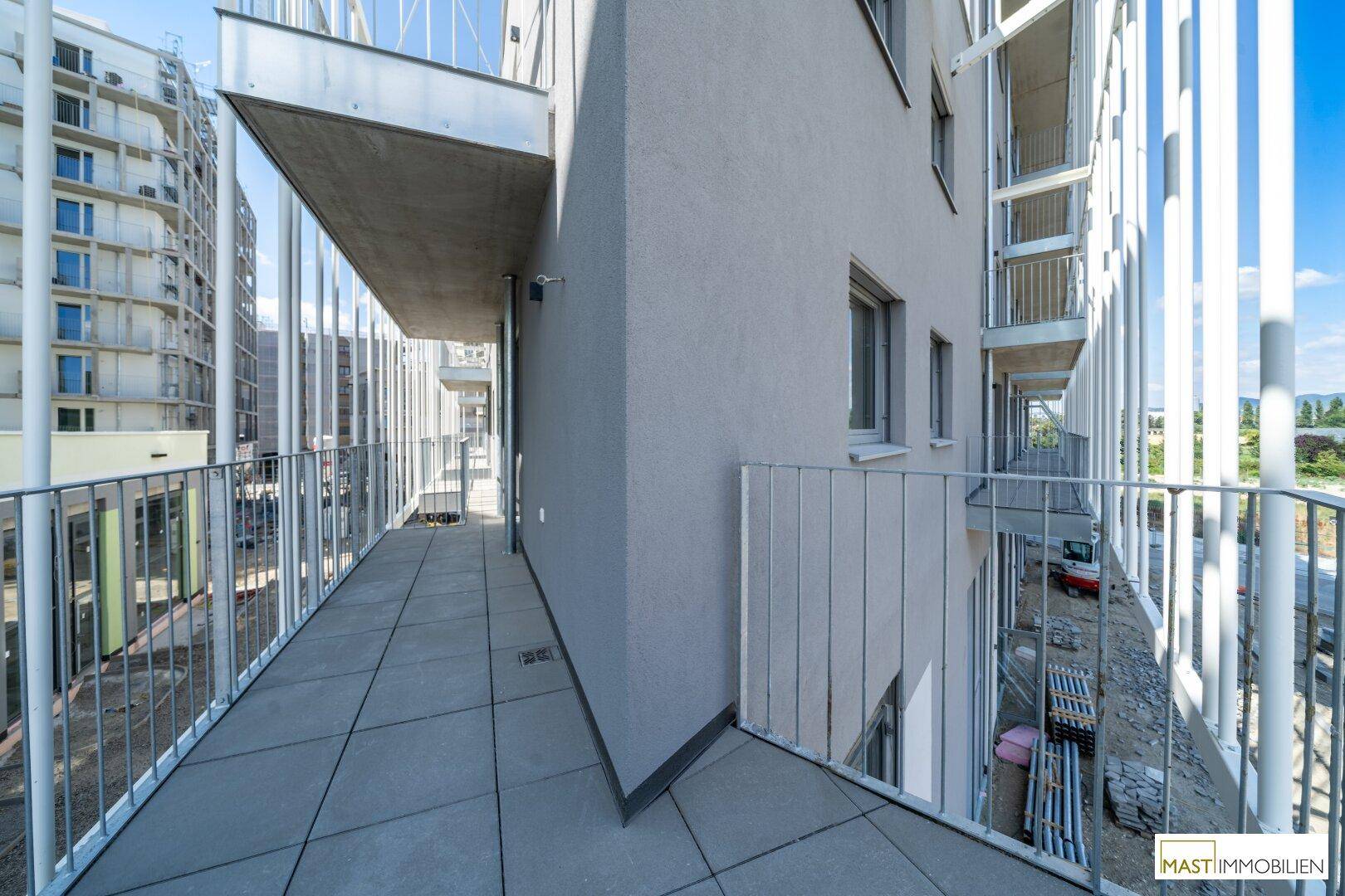 Langer Balkon mit moderner Architektur und Blick auf die umliegende Bebauung und Natur.