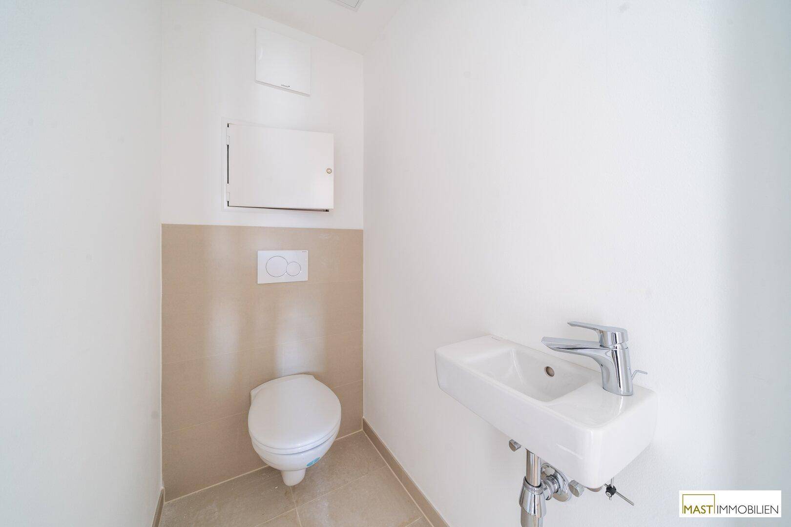 Modernes Gäste-WC mit wandhängender Toilette, kleinem Waschbecken und hellen Fliesen.