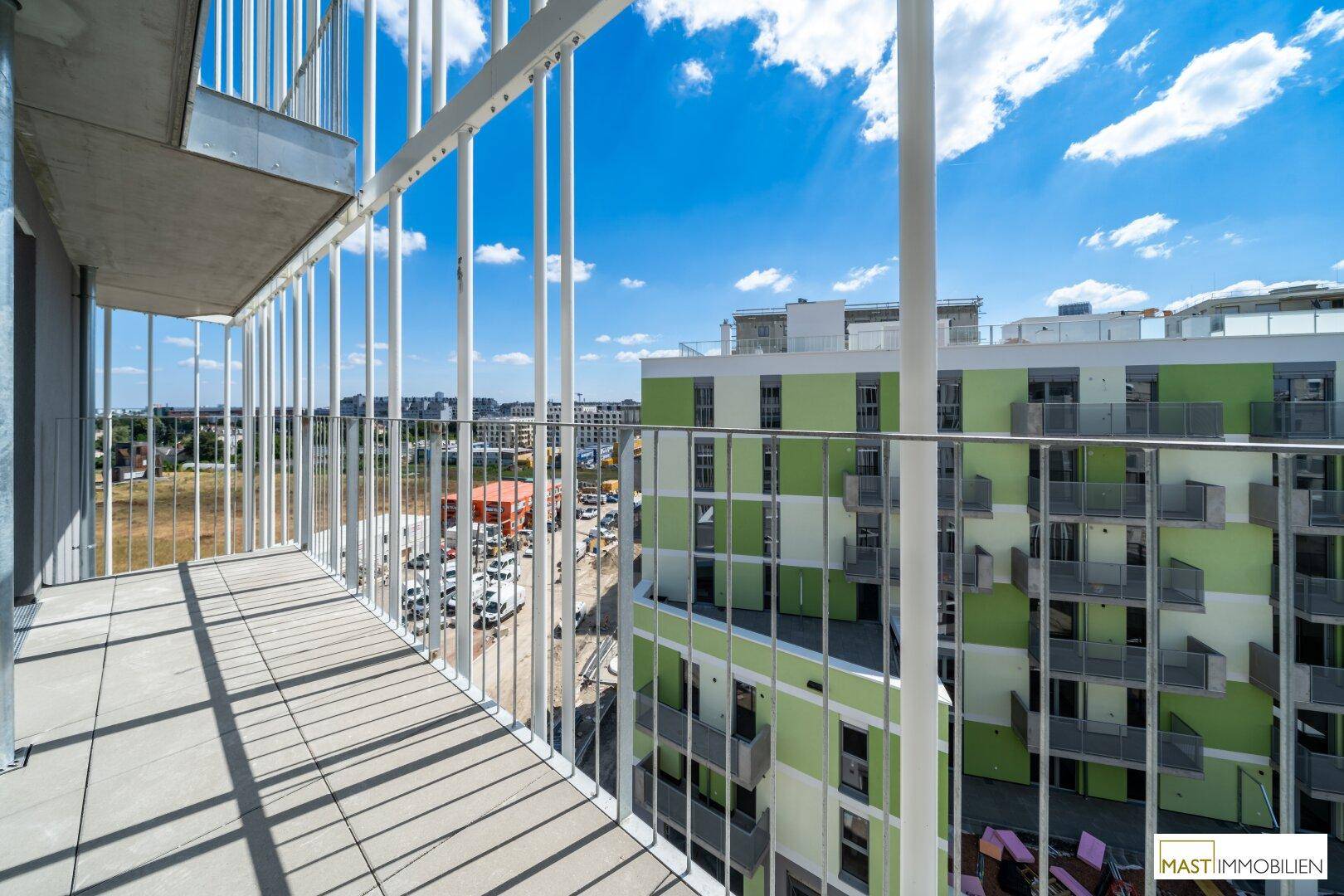 Geräumiger Balkon mit Fliesenboden und weitem Blick auf die umliegenden Gebäude und die Stadt.