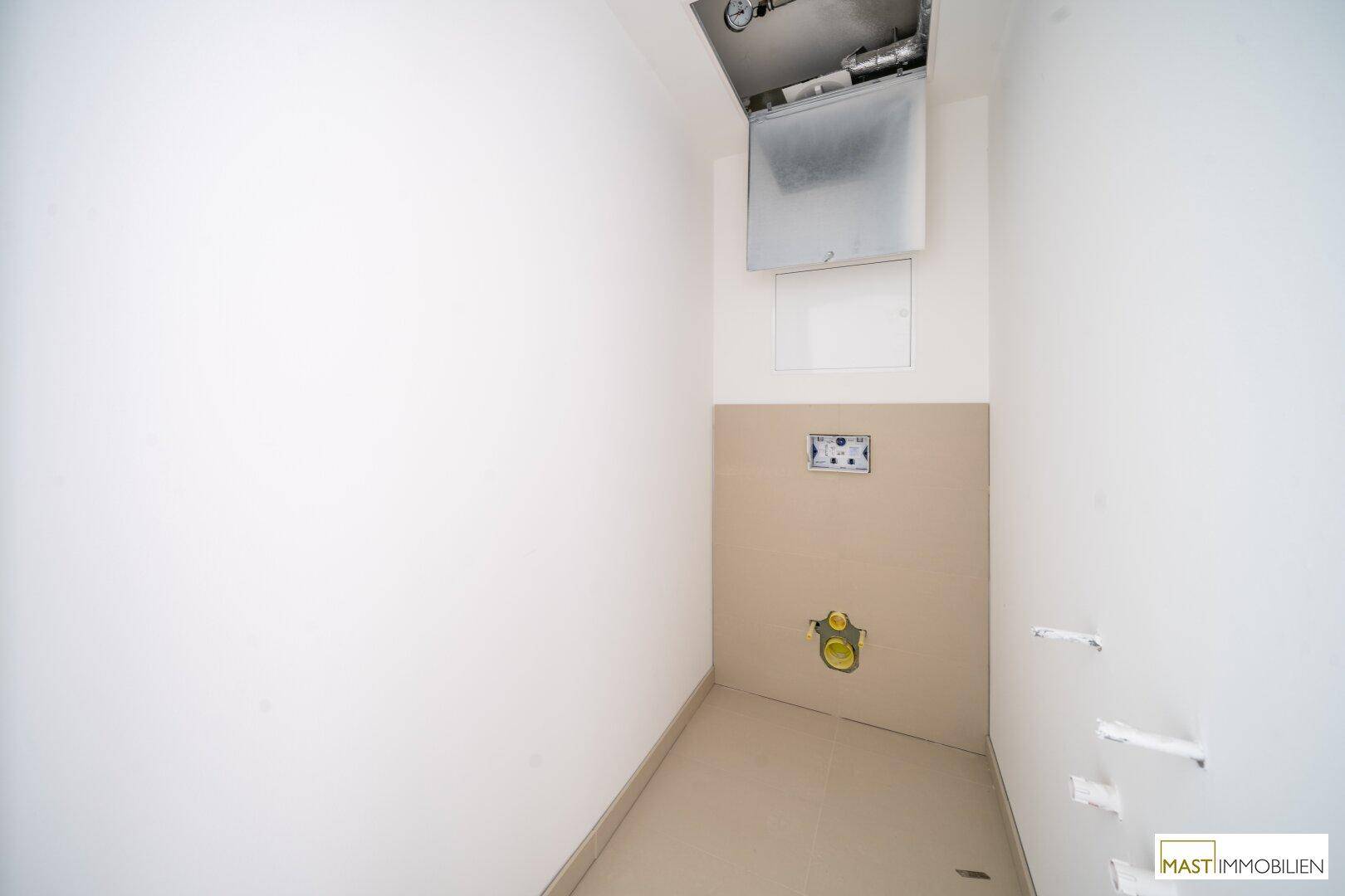 Kleiner Raum mit Fliesenboden und vorbereiteten Anschlüssen für ein WC, inklusive Lüftungssystem.