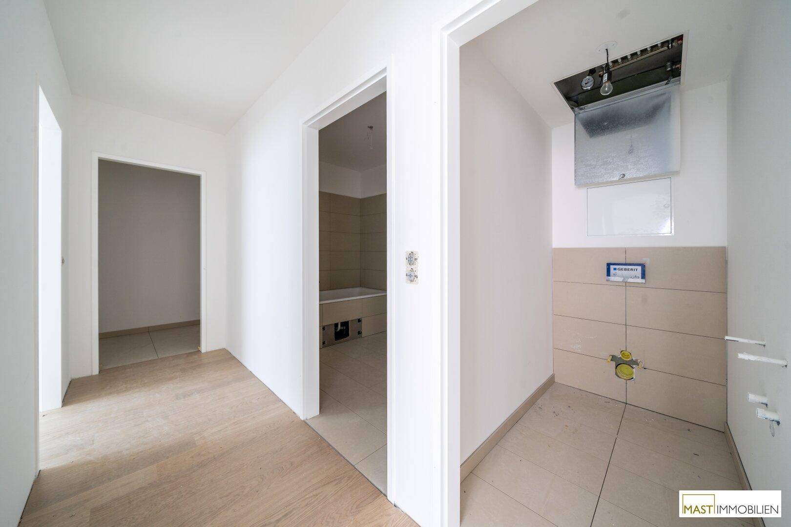 Flur mit Zugang zu einem Badezimmer und einem vorbereiteten Bereich für ein Gäste-WC.