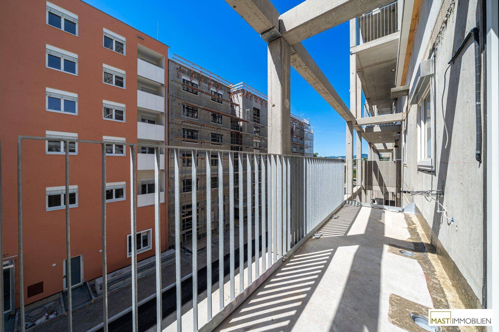 Balkon im Bau mit Blick auf die umliegenden Neubauten und die städtische Umgebung.