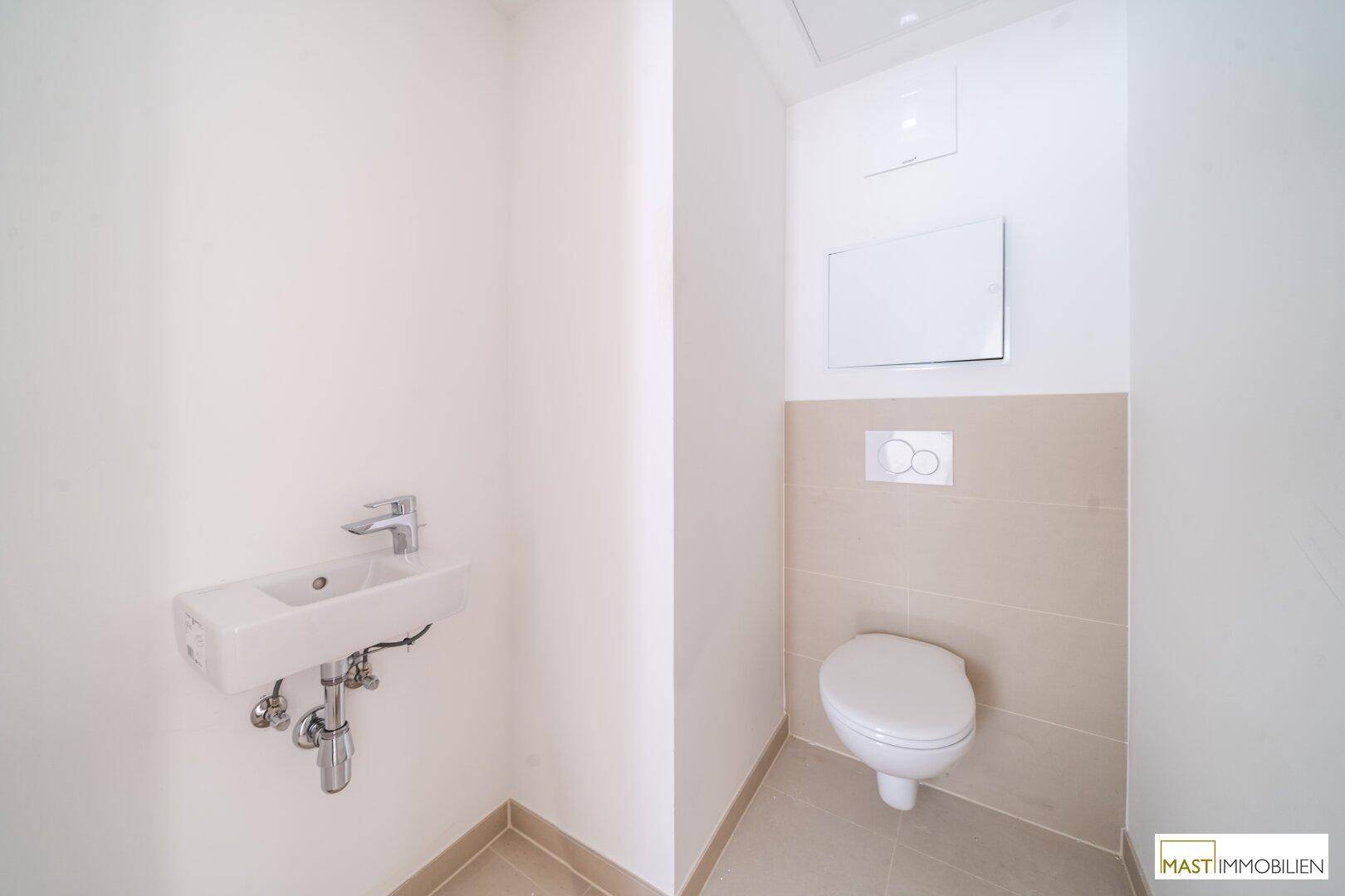 Modernes Gäste-WC mit wandhängendem WC und kleinem Waschbecken in hellen Farbtönen.