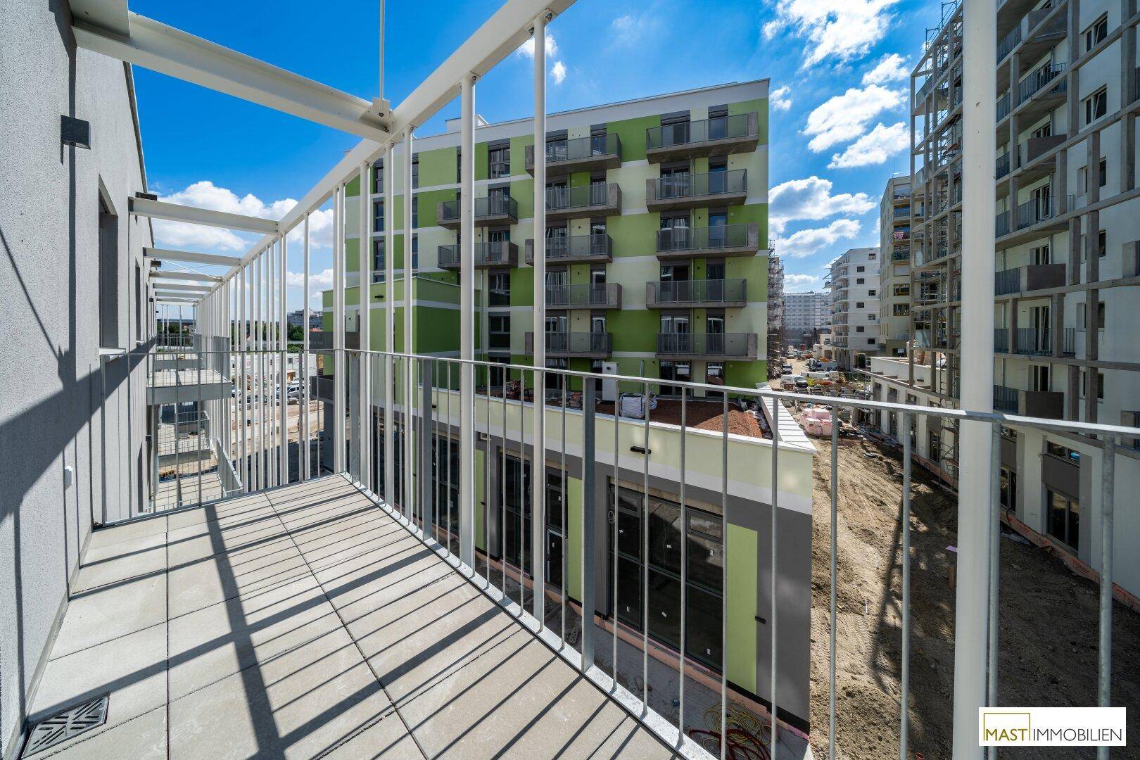 Geräumiger Balkon mit Fliesenboden und Blick auf moderne Wohngebäude in der Umgebung.