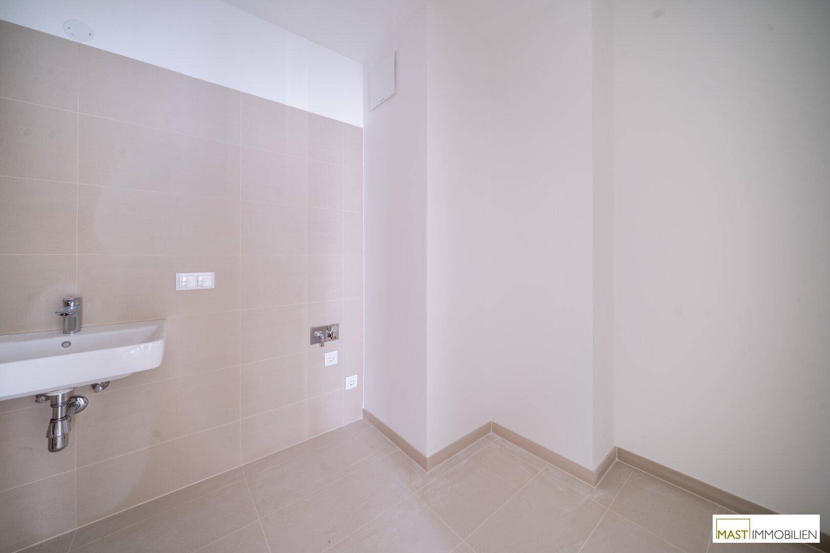 Funktionaler Raum mit Fliesenboden und Waschbecken, vorbereitet für weitere Installationen oder als Hauswirtschaftsraum.