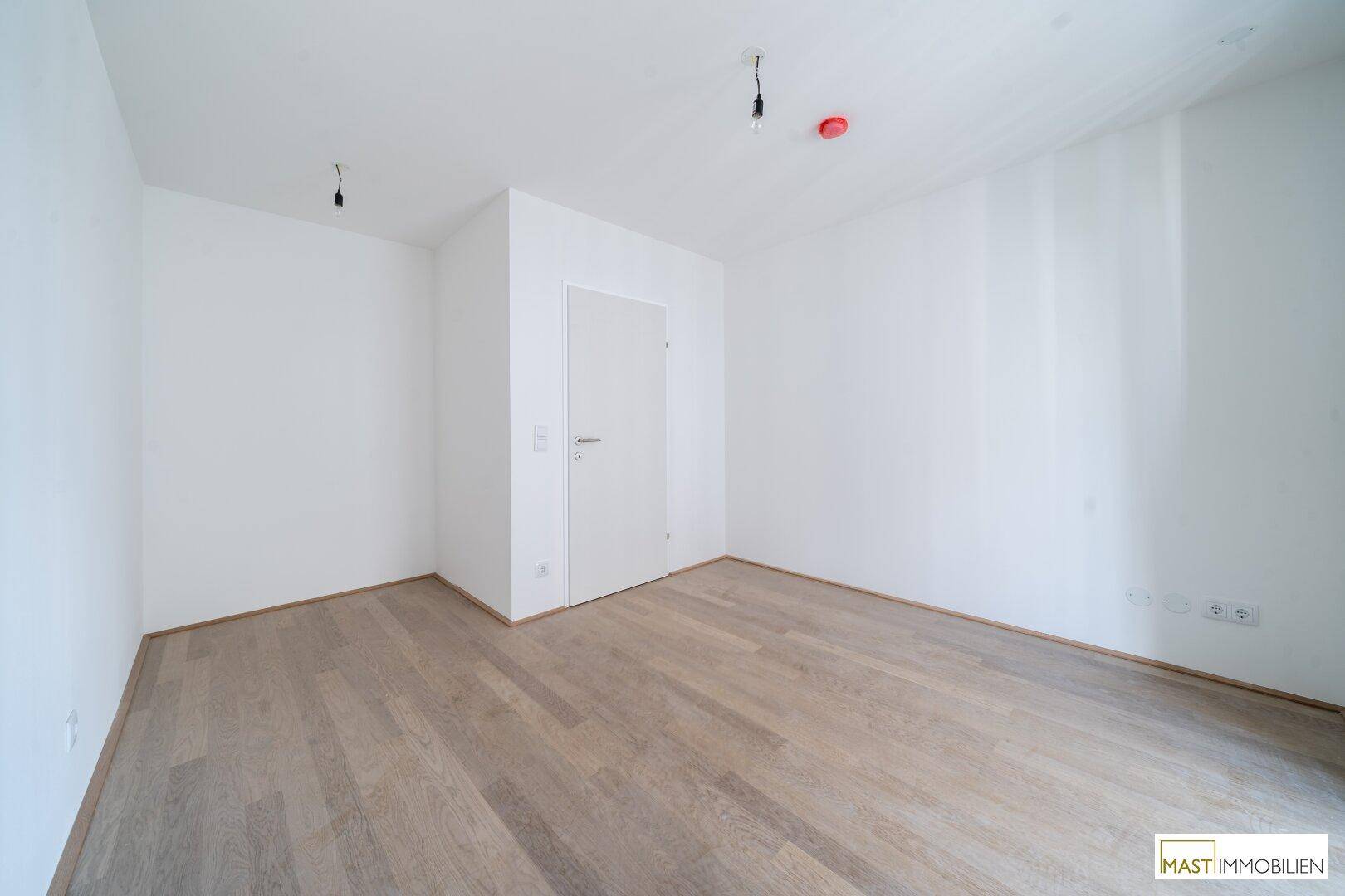 Leeres Zimmer mit hellem Parkettboden und weißen Wänden, bietet vielseitige Gestaltungsmöglichkeiten.