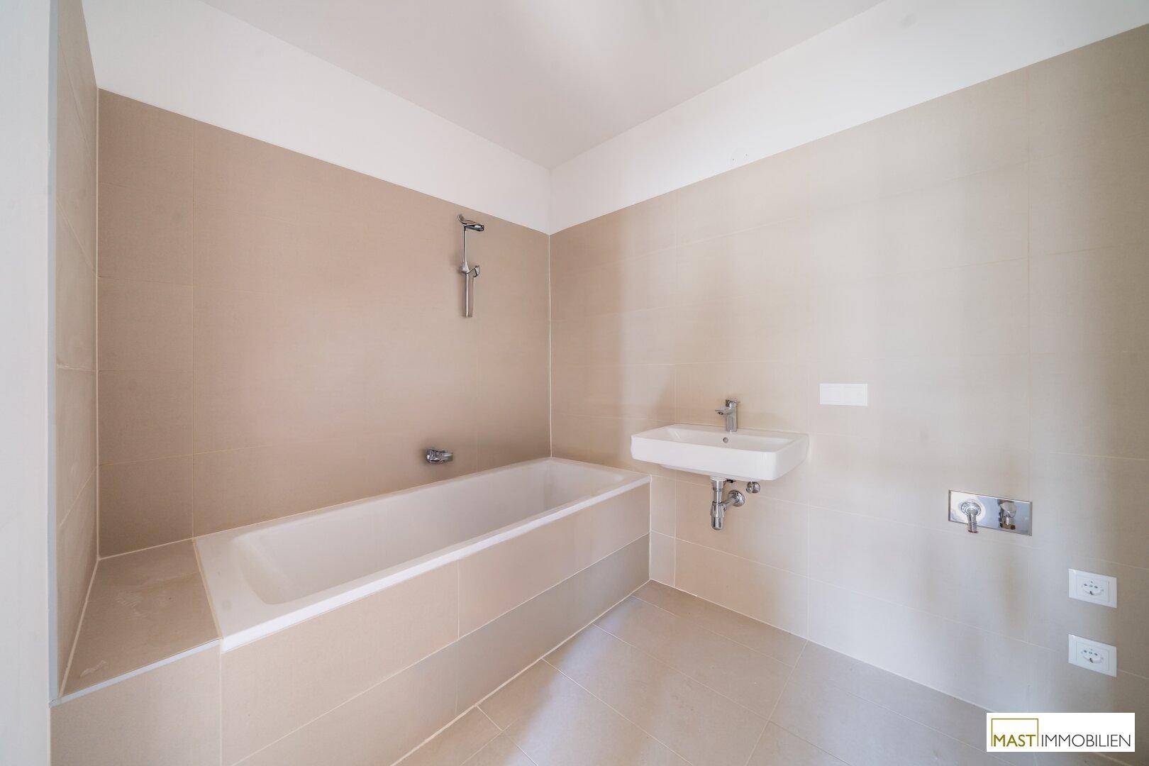 Modernes Badezimmer mit Badewanne und Waschbecken, ausgestattet mit beigefarbenen Fliesen.