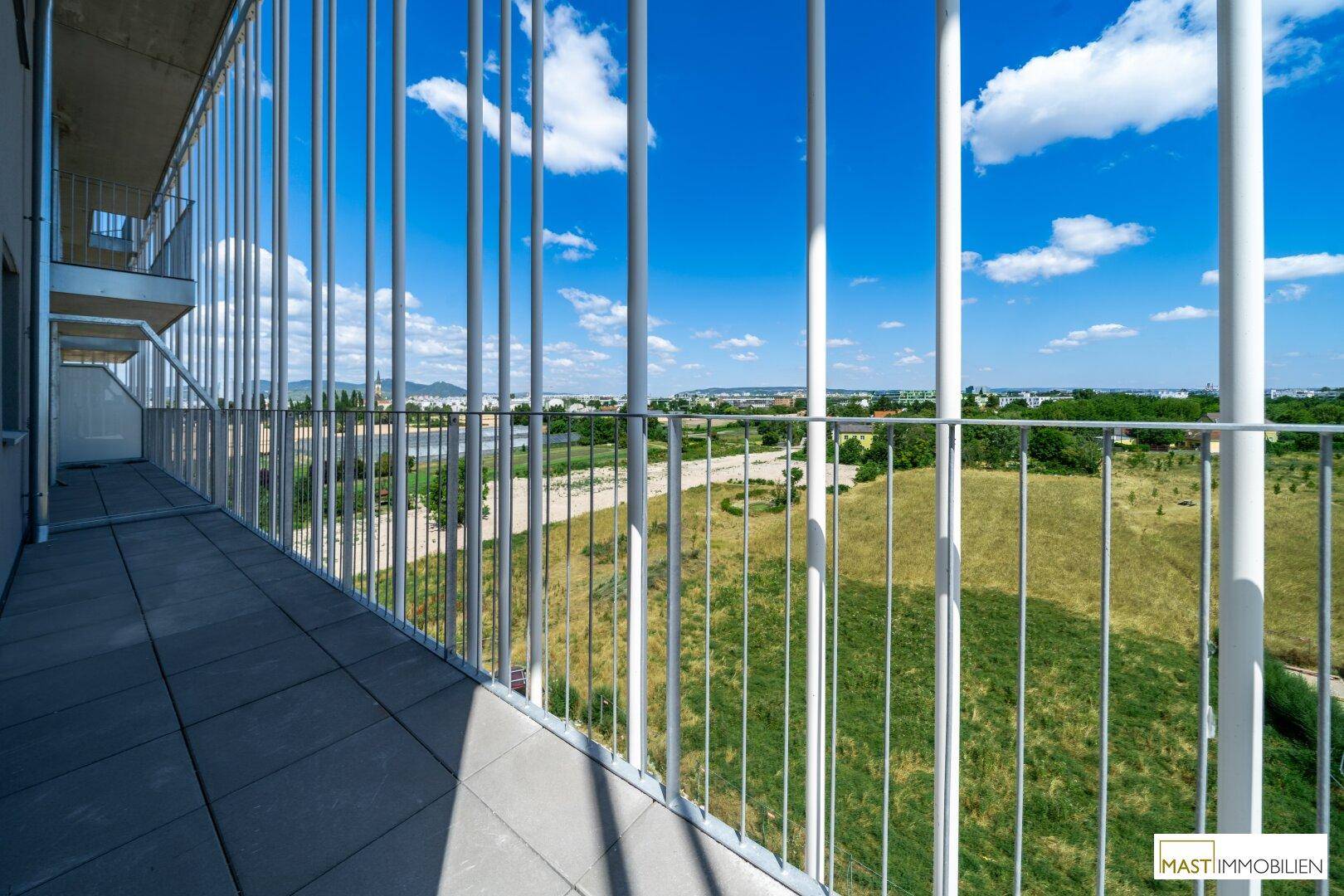 Heller Balkon mit Fliesenboden und weitem Blick über grüne Felder und die Landschaft.
