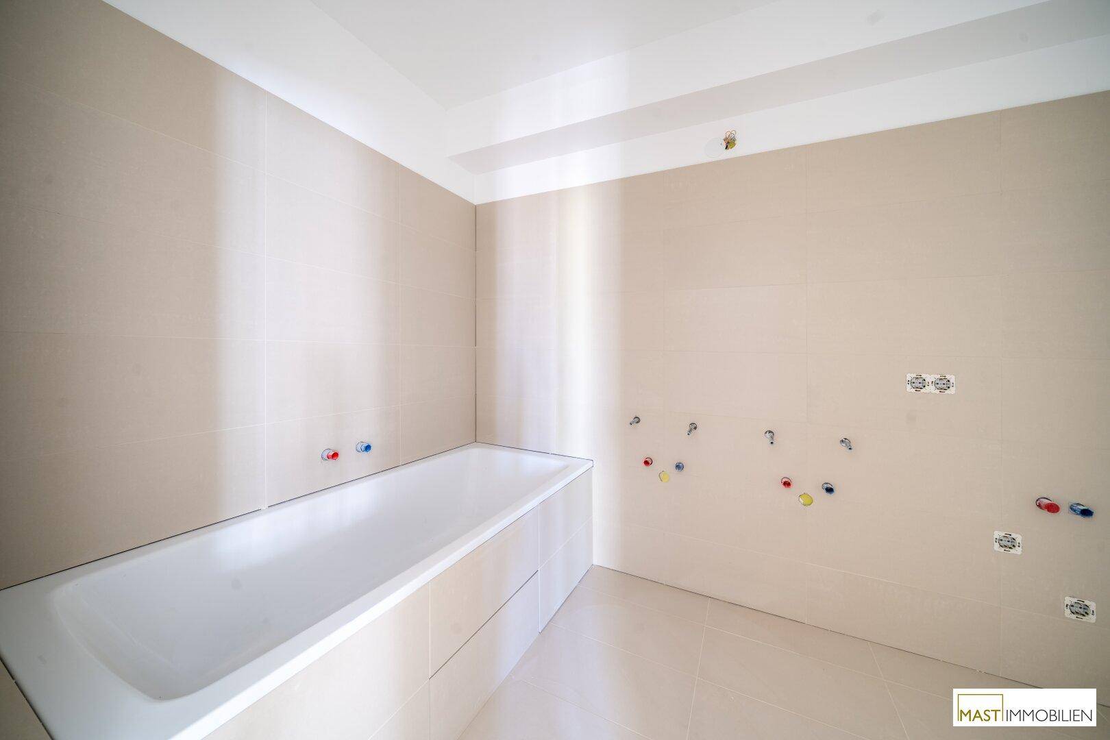 Unfertiges Badezimmer mit eingebauter Badewanne und Fliesen, bereit für die Endmontage.