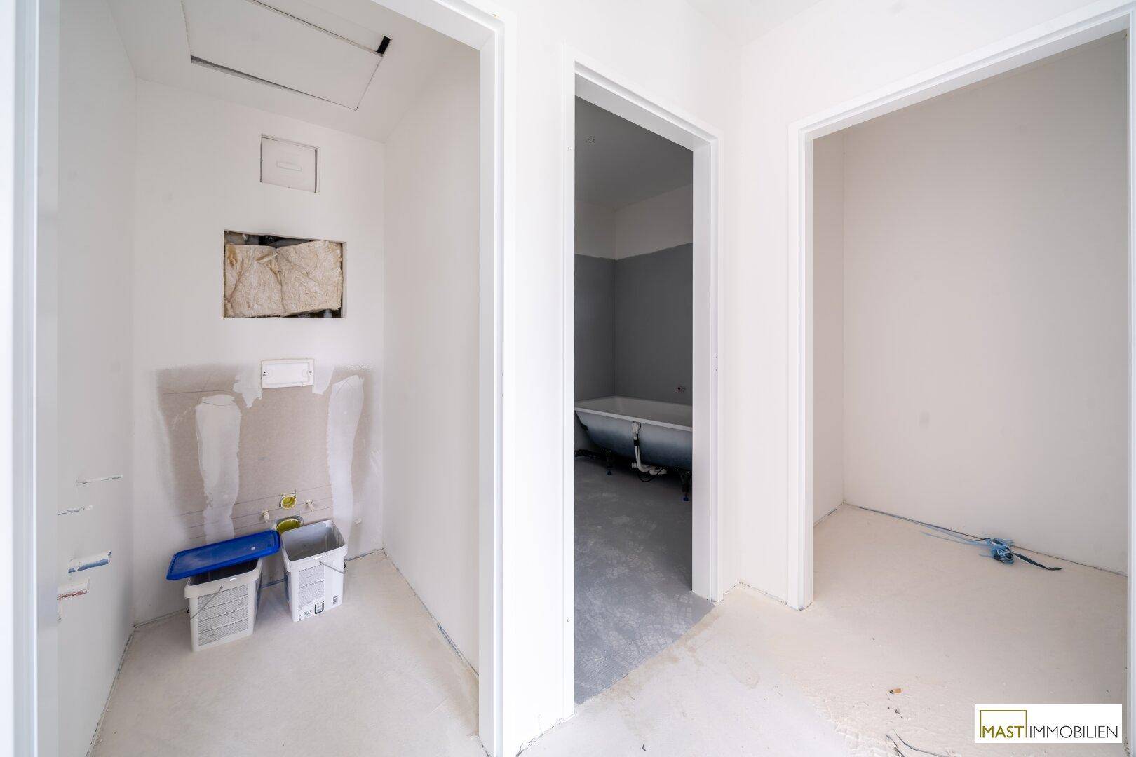 Flur mit Zugängen zu verschiedenen Räumen, darunter ein Badezimmer im Rohbau.