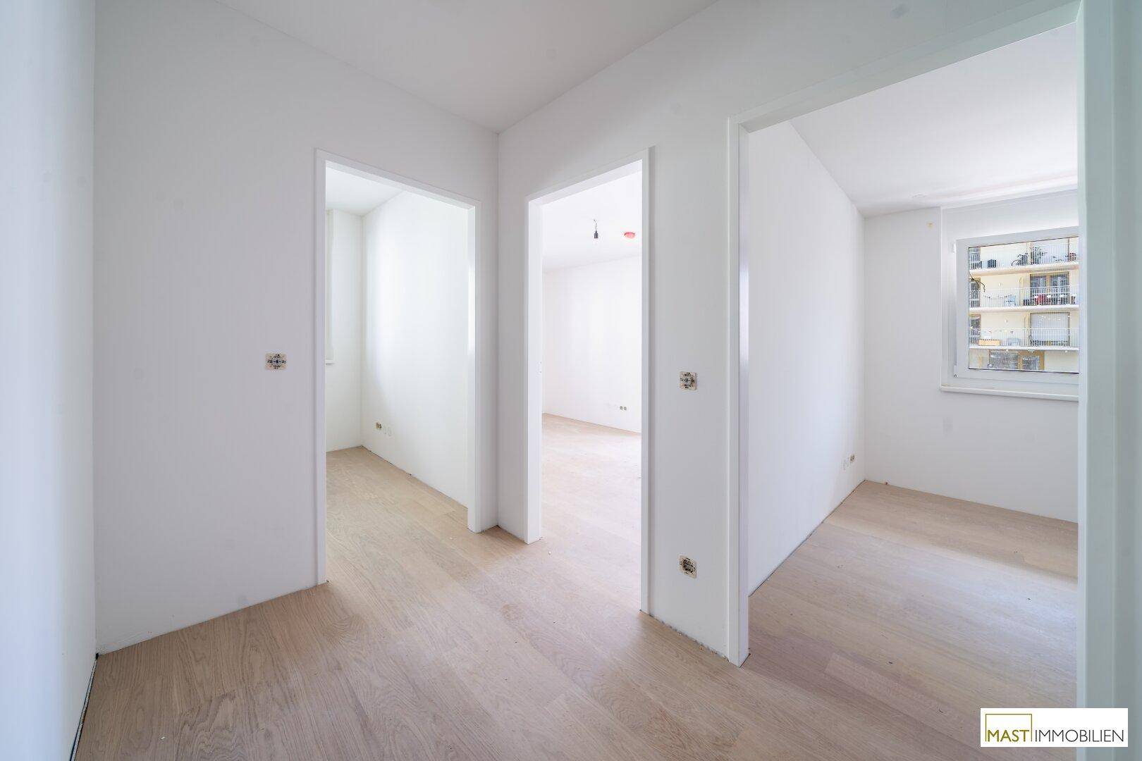 Heller Flur mit Holzboden und mehreren Türen, die zu den angrenzenden Räumen führen.