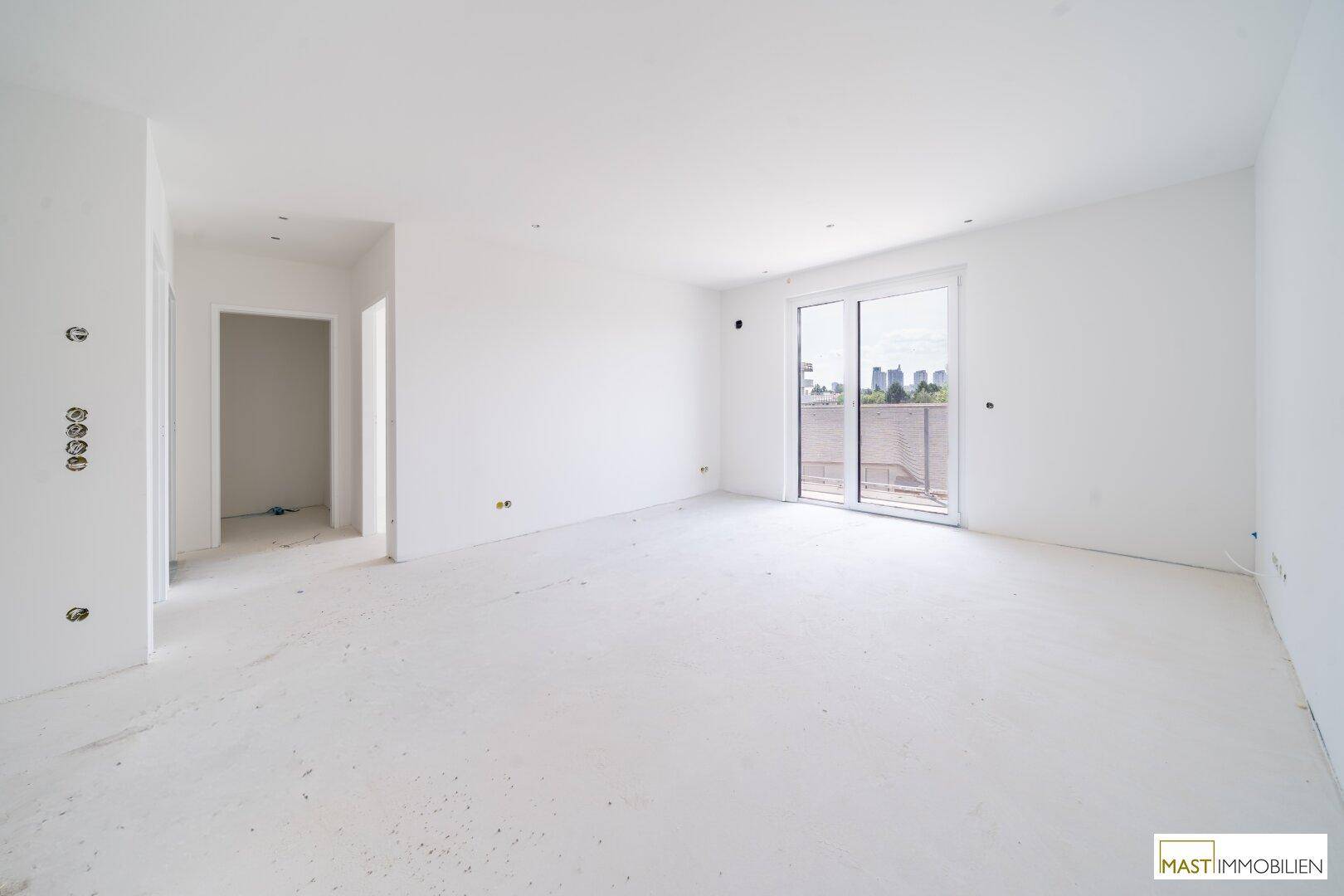 Heller, unmöblierter Raum mit großen Schiebetüren zum Balkon, bereit für den Innenausbau.