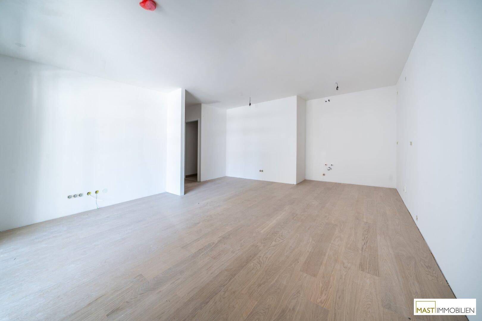 Weitläufiger Wohnbereich mit hellem Laminatboden und vielen Steckdosen für flexible Nutzung.