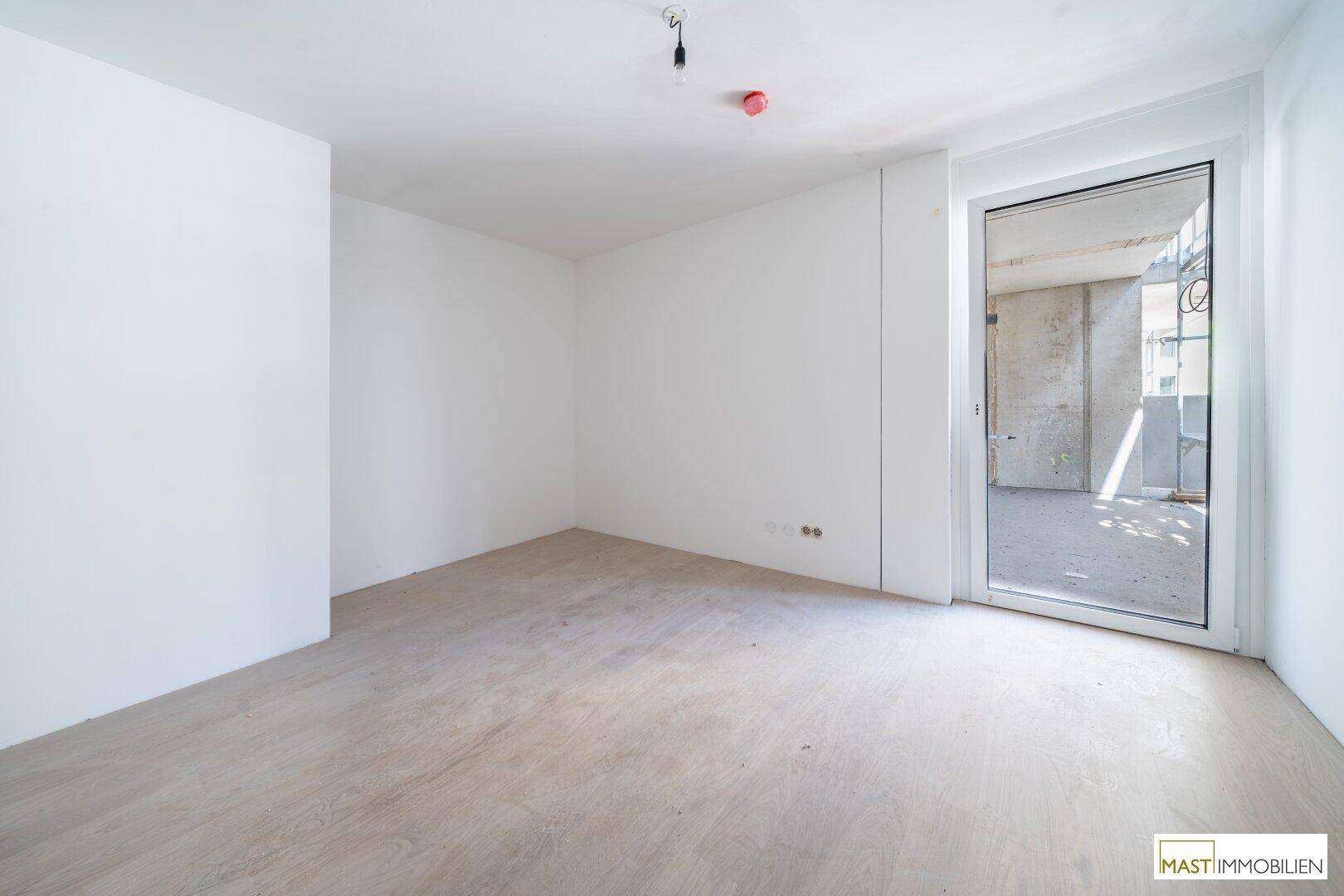 Helles Schlafzimmer mit Laminatboden und großem Fenster zu einem noch unfertigen Außenbereich.